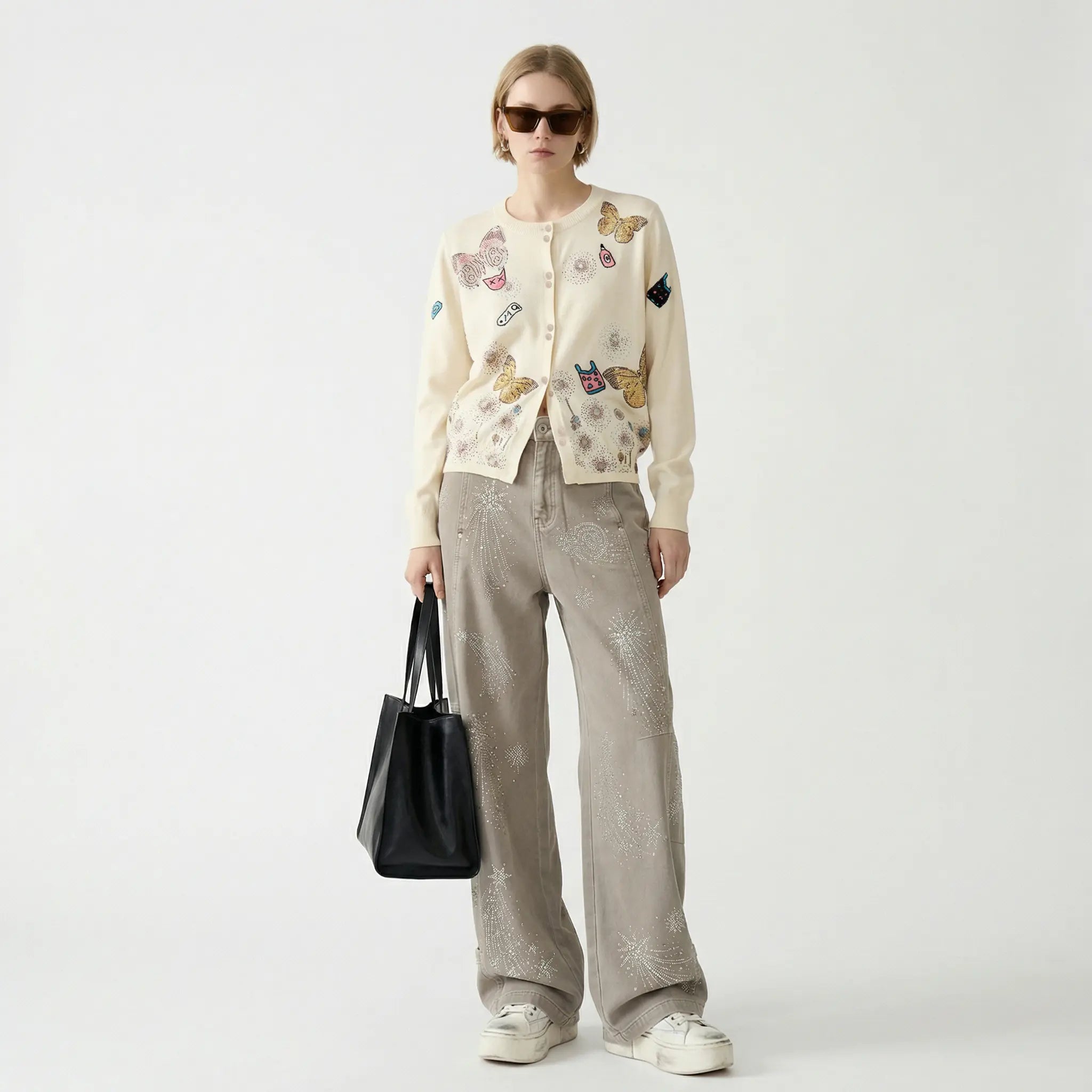 Person wearing a patterned cardigan and holding a black bag on a white background, TCH Celestial Firework Rhinestone Wide-Leg Pants