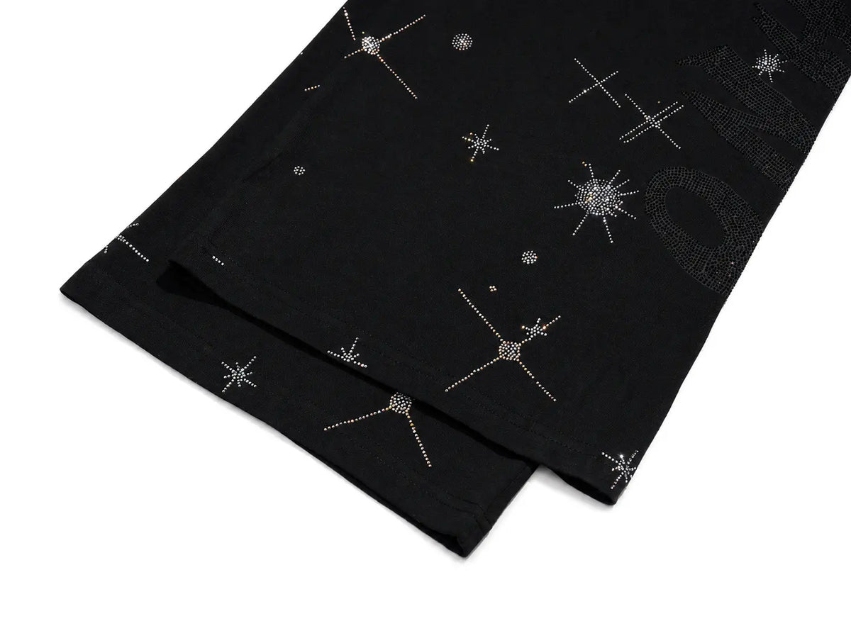 Black fabric with scattered silver rhinestone starburst and dot patterns, folded on a white background. TCH Celestial Rhinestone Wide-Leg Sweatpants