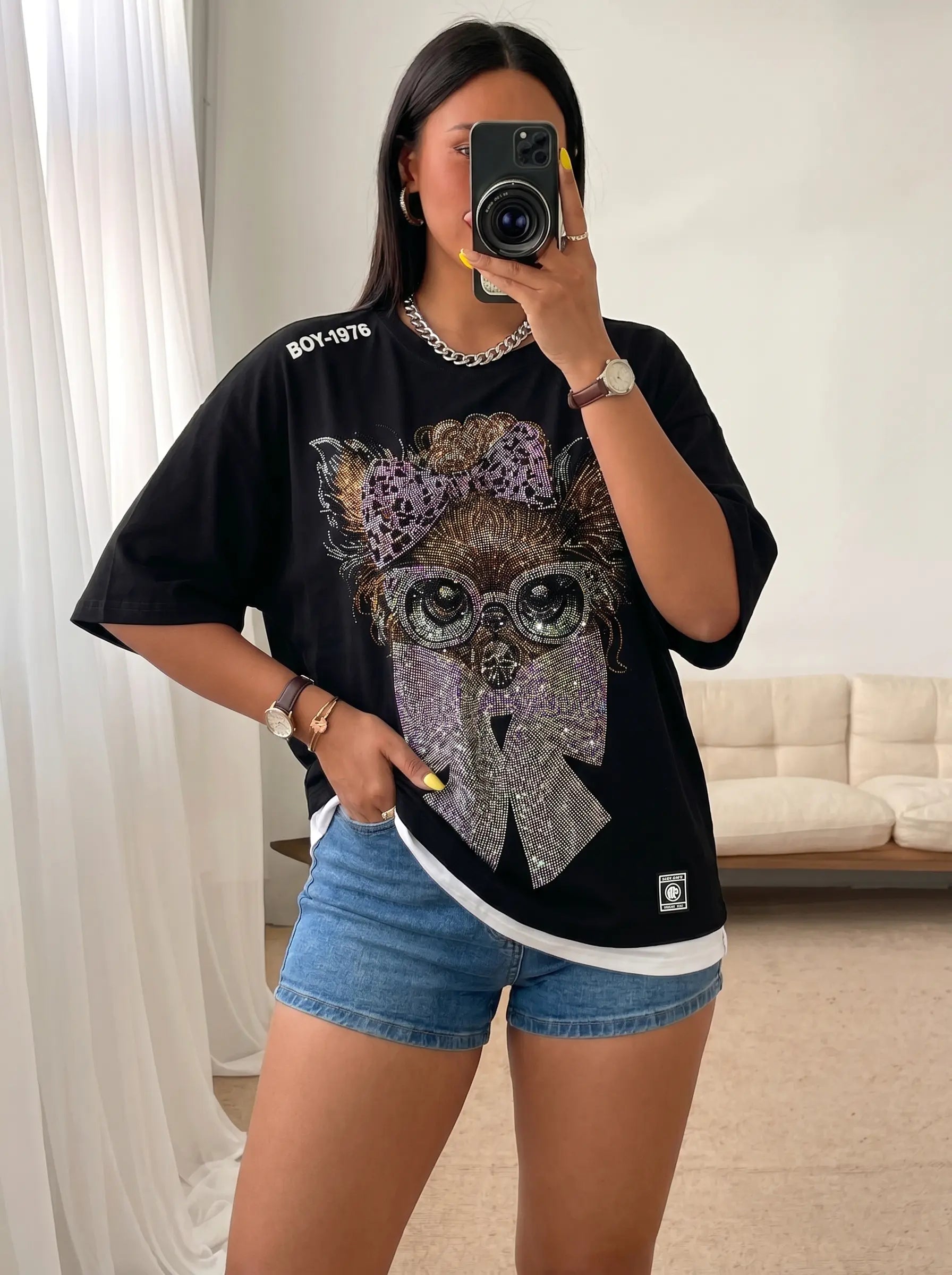Person wearing a black t-shirt with an owl design and denim shorts indoors. TCH Chihuahua Bow Rhinestone T-Shirt