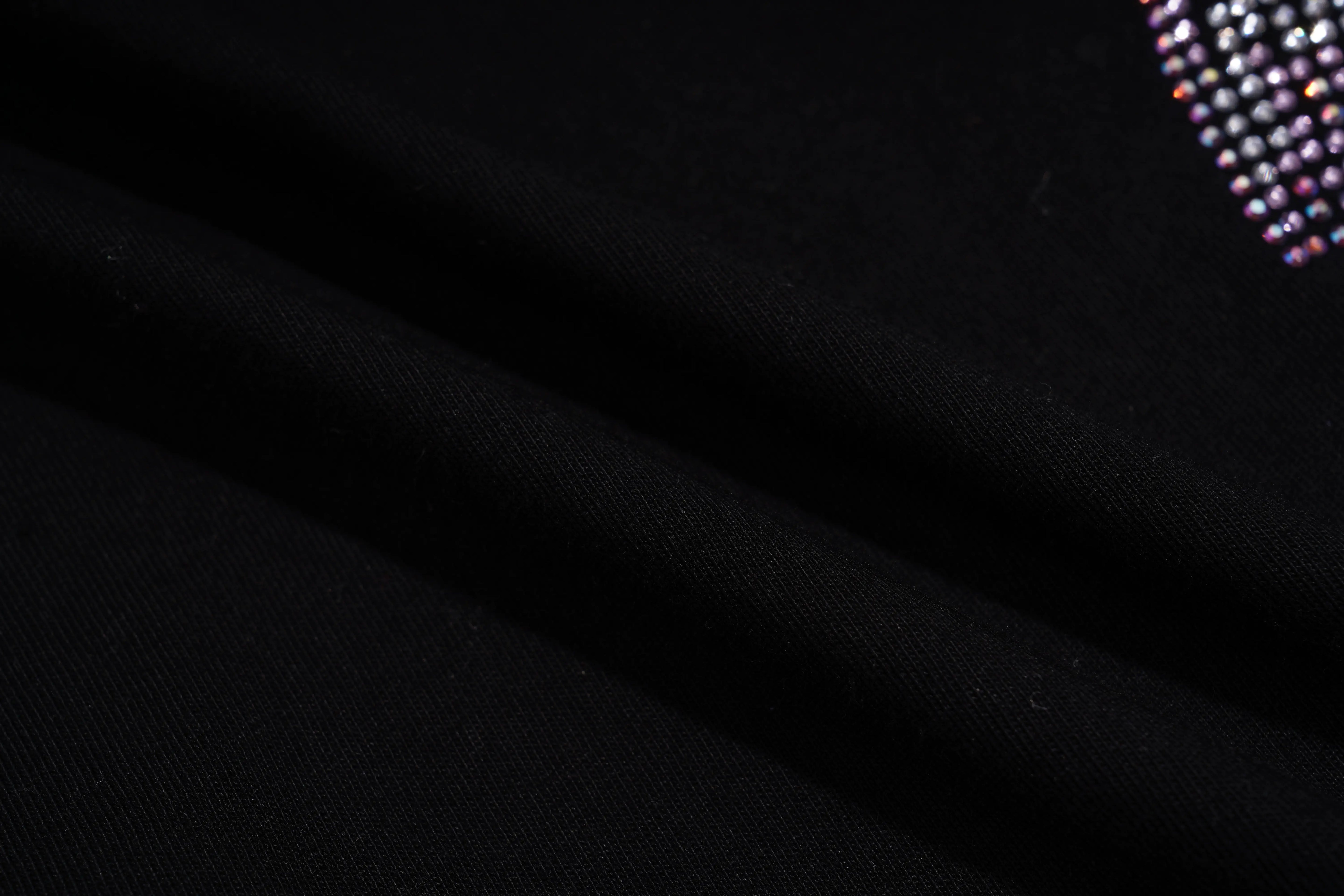Close-up of black fabric with a textured pattern on a dark background, TCH Chihuahua Bow Rhinestone T-Shirt