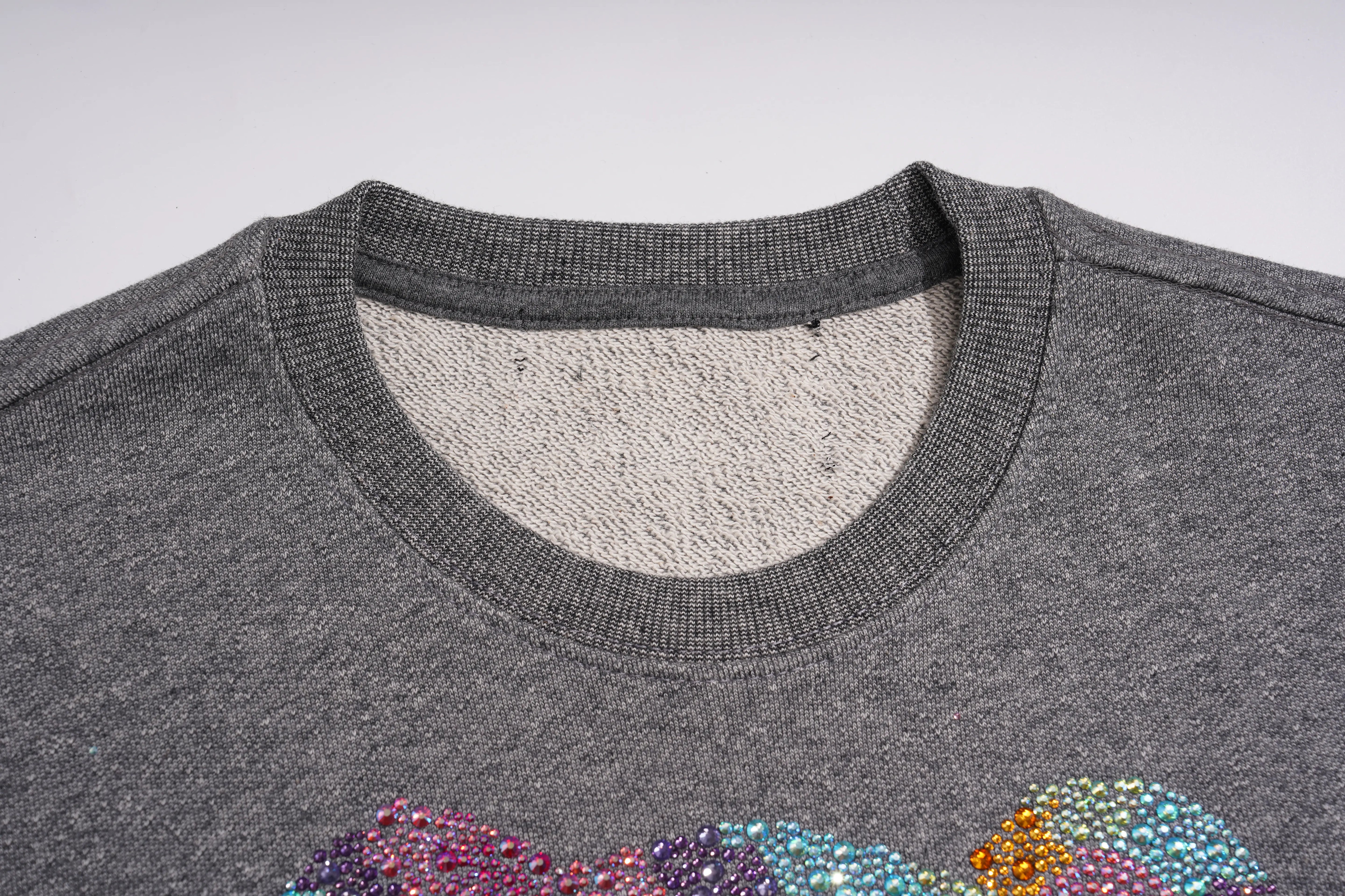 Close-up of a dark gray crewneck sweater showing the ribbed collar and a colorful rhinestone graphic at the bottom. TCH Colorful Rhinestone Teddy Bear Crewneck Sweatshirt