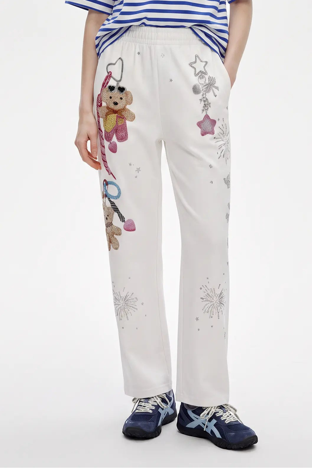 White wide-leg sweatpants with teddy bear and star embroidery, styled with a blue striped t-shirt and blue sneakers. TCH Crystal Bear Graphic Wide-Leg Sweatpants