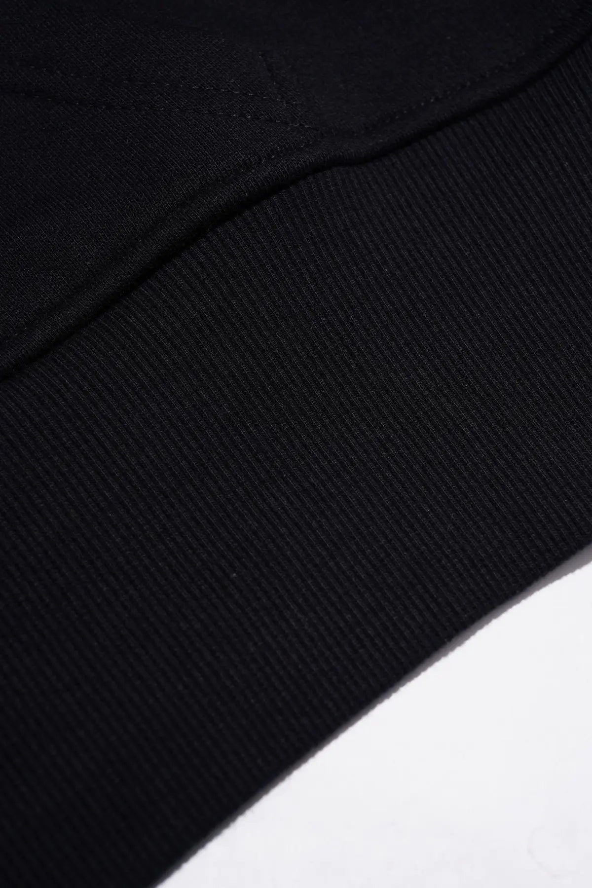 Close-up detail of a black ribbed knit fabric, showing the texture and stitching of a garment. TCH Crystal Eagle Graphic Zip Up Hoodie