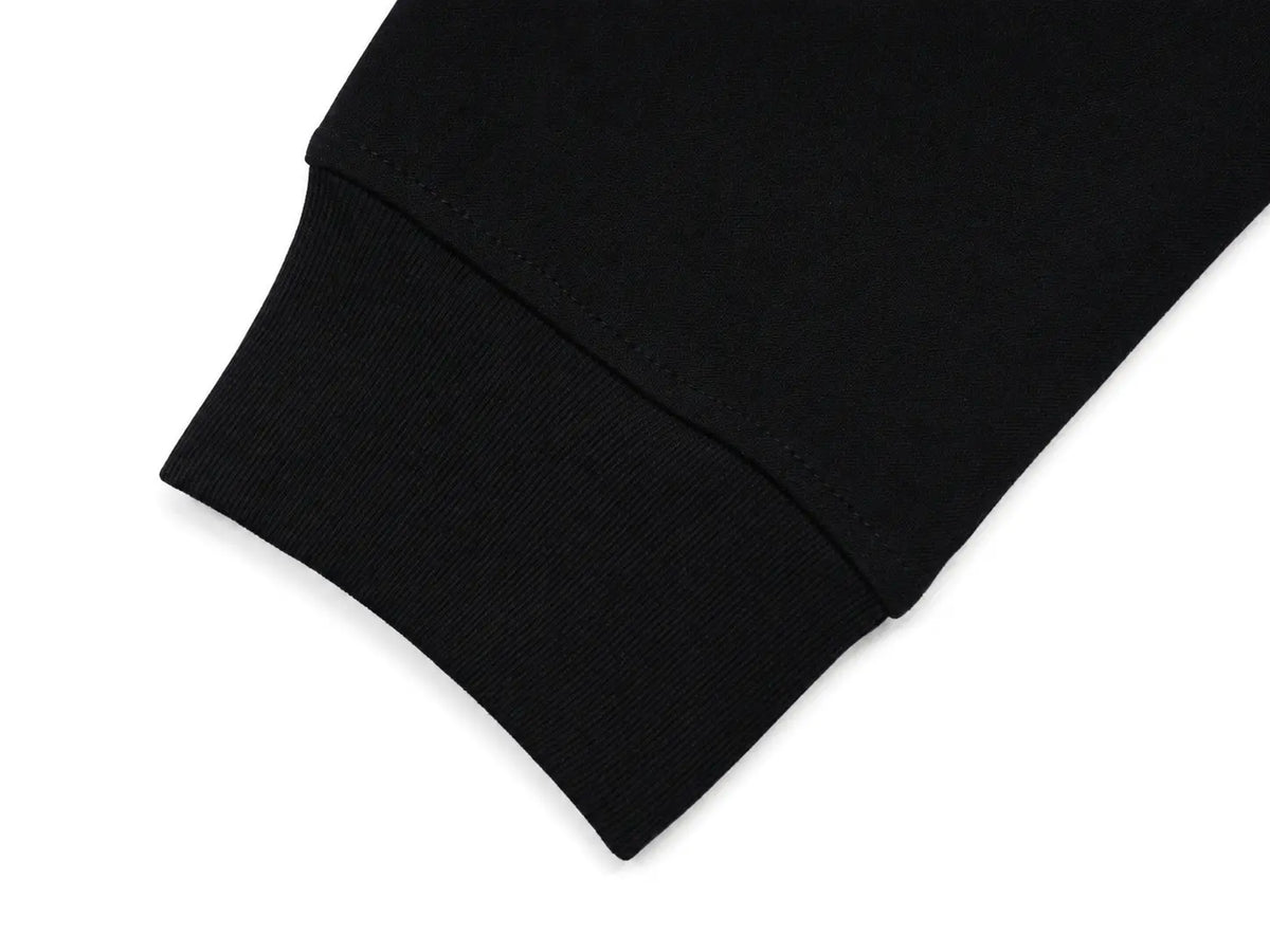 Close-up of a black ribbed knit cuff, likely on a sweatshirt or sweater sleeve, shown against a plain white background. TCH Crystal Wing Graphic Zip Up Hoodie