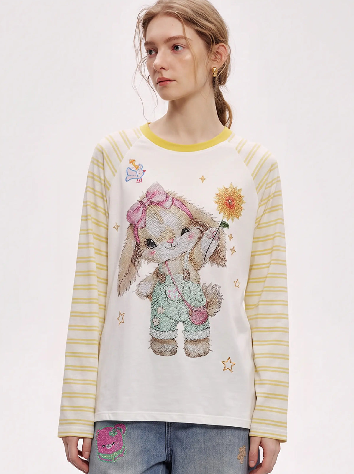 A model wearing a light blue denim jacket with various embroidered patches, including a teddy bear on the left chest and cherries on the sleeve, styled over a white t-shirt and dark pants. TCH Cute Bunny Rhinestone Graphic Striped Sleeve Long Sleeve T-Shirt