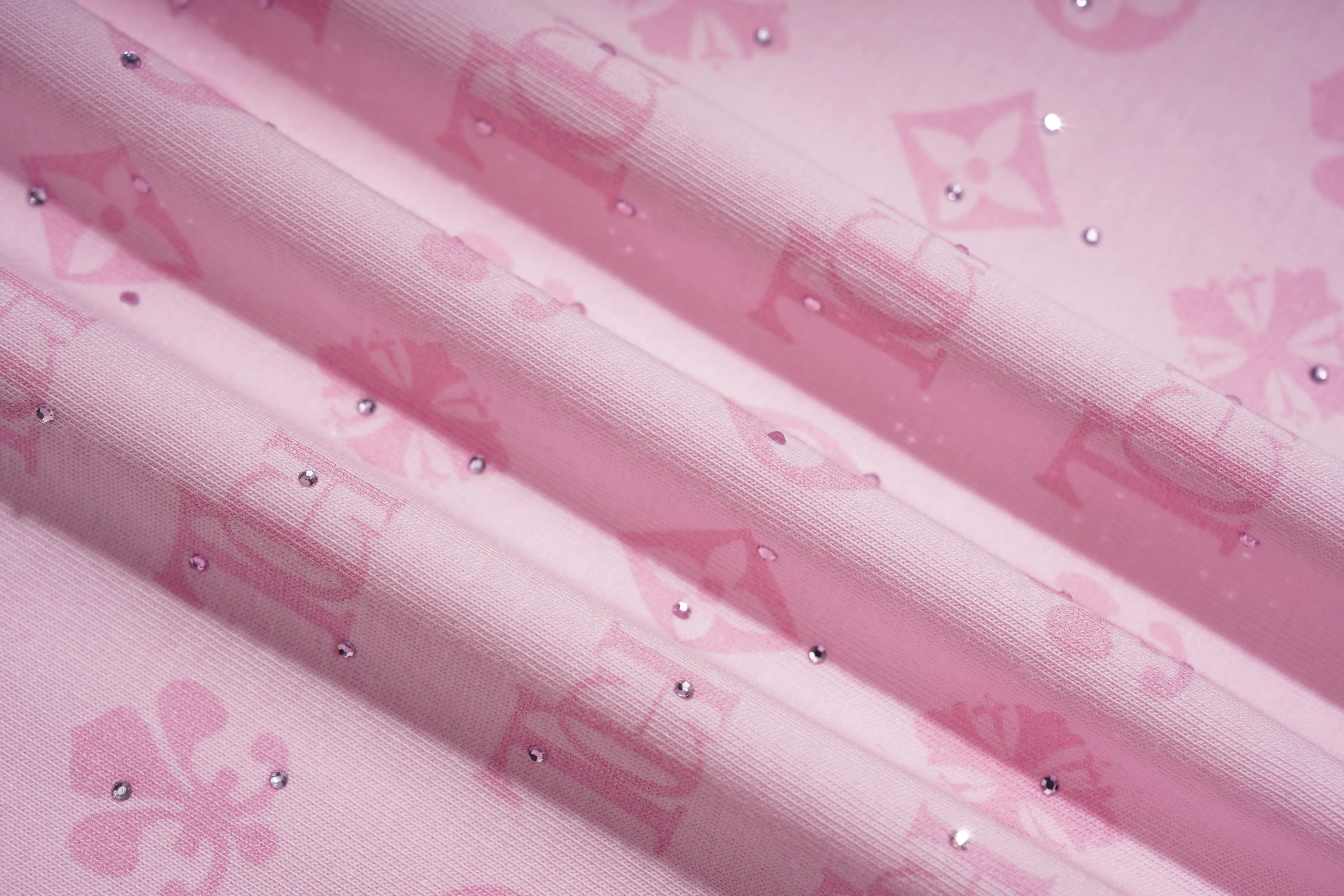 Pink fabric with a repeating monogram-style pattern and scattered small rhinestone embellishments, shown in soft folds. TCH Cute Hoodie Teddy Bear Rhinestone Oversized T-Shirt Dress