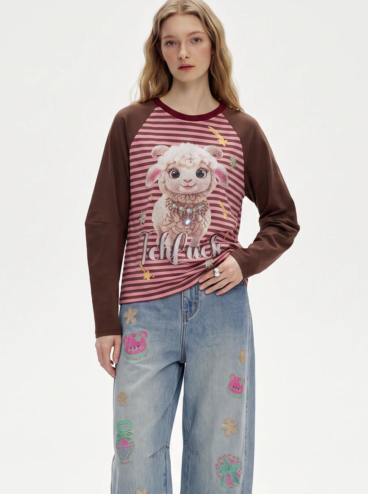 A model wearing a brown and pink striped long-sleeve t-shirt with a cartoon sheep graphic and the text 'Iehlfuck' on the front, paired with light blue jeans decorated with small colorful patches. TCH Cute Lamb Pink Striped Raglan Long Sleeve Top