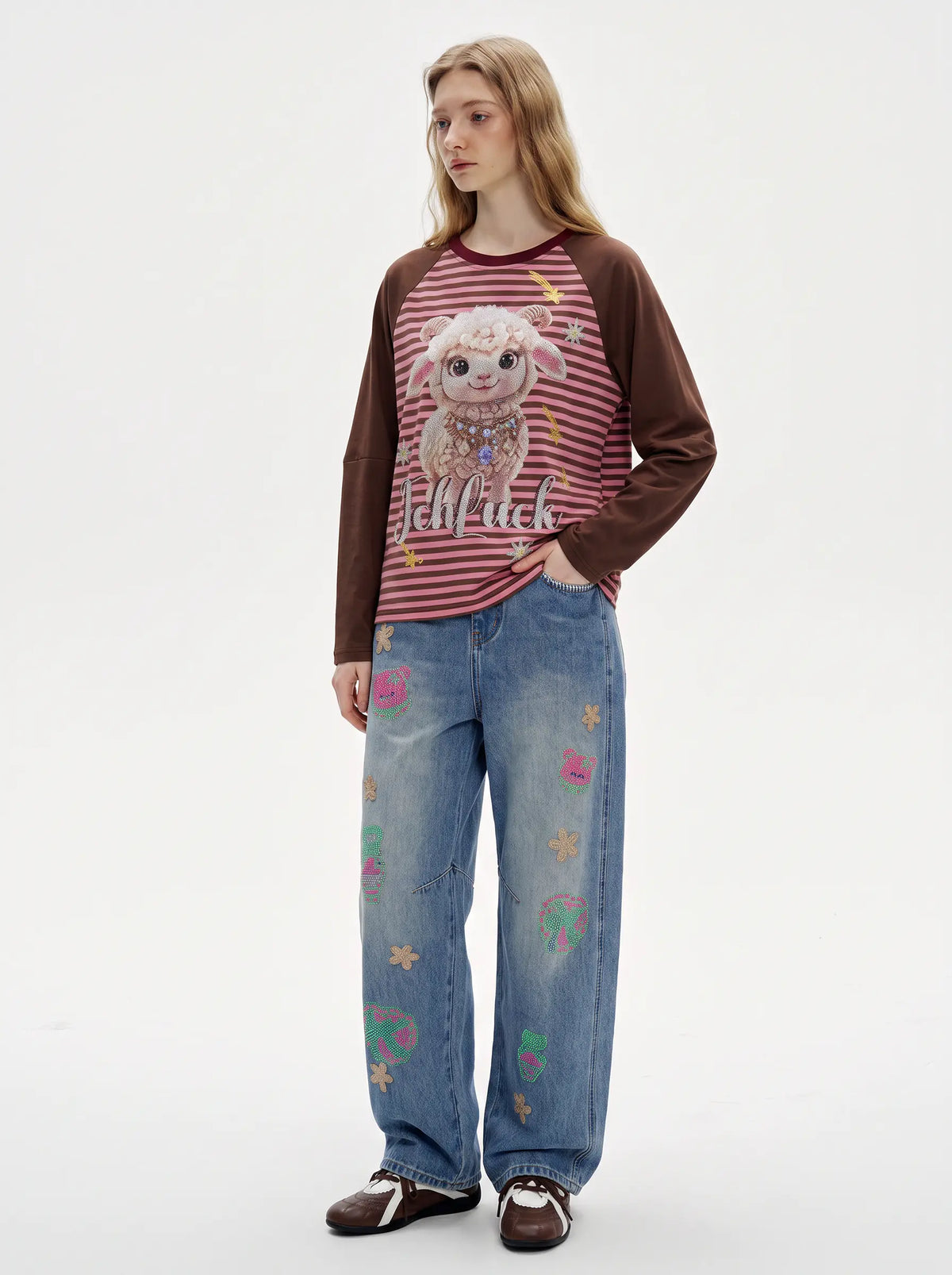 A model stands against a plain white studio background wearing a long-sleeve raglan shirt with brown sleeves and a red-and-white striped body featuring a cartoon sheep graphic and the word 'Kiffkiff'. She is also wearing light blue jeans with colorful embroidered details and dark brown loafers. TCH Cute Lamb Pink Striped Raglan Long Sleeve Top