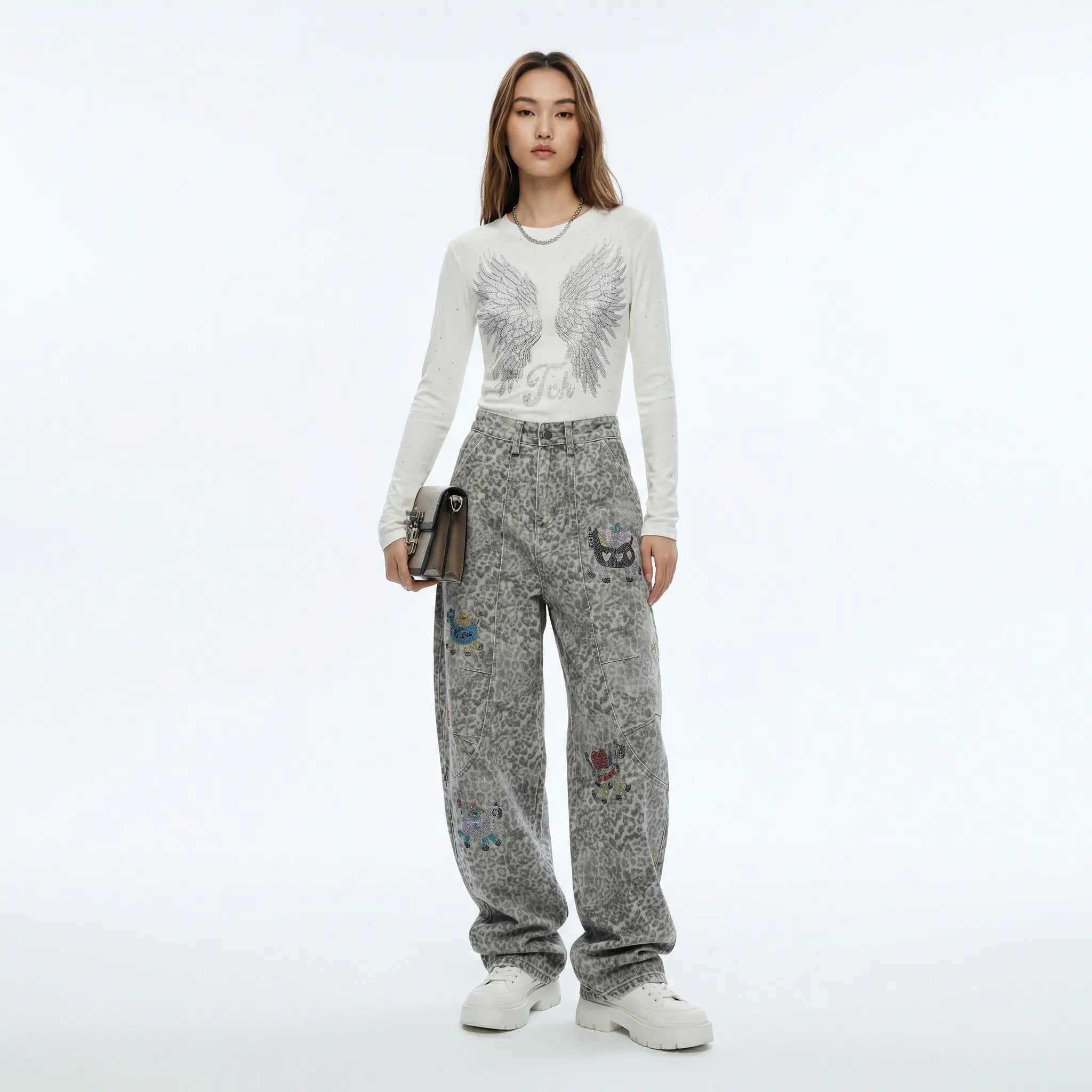 Person wearing a white long-sleeve top with a graphic design and gray sweatpants with colorful patches on a white background, TCH Cute Pony Rhinestone Grey Leopard Wide-Leg Jeans