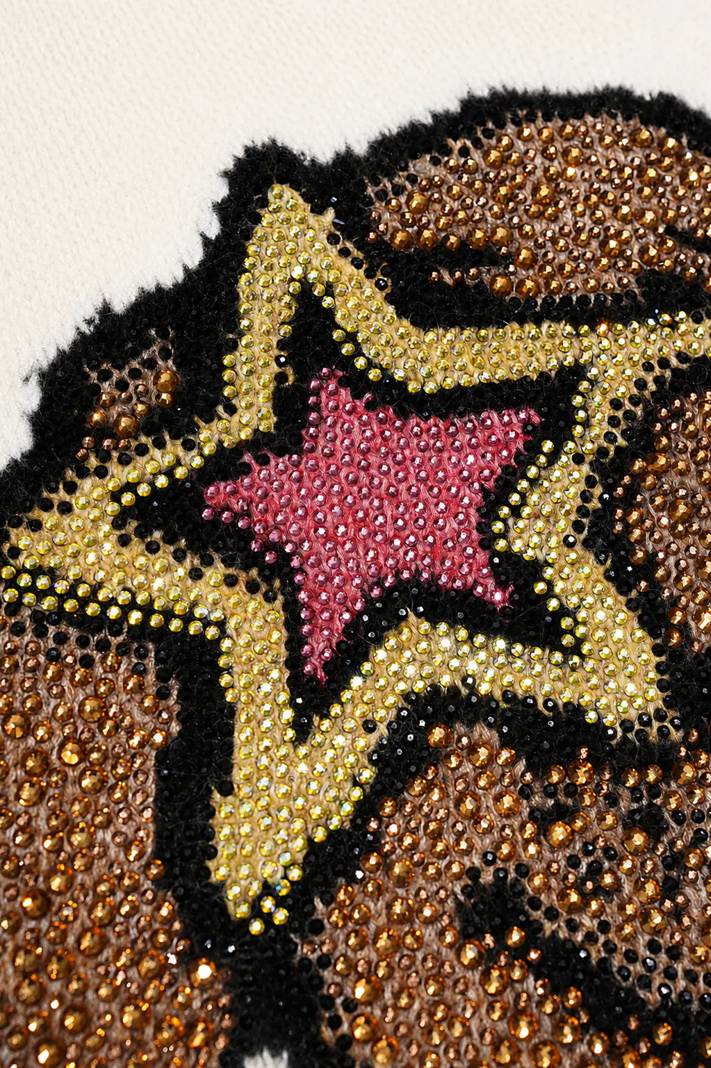 Close-up of a beaded star patch featuring a pink center surrounded by a gold beaded border, all outlined in black, with a brown patterned background. TCH Cute Puppy Star Graphic Knit Sweater