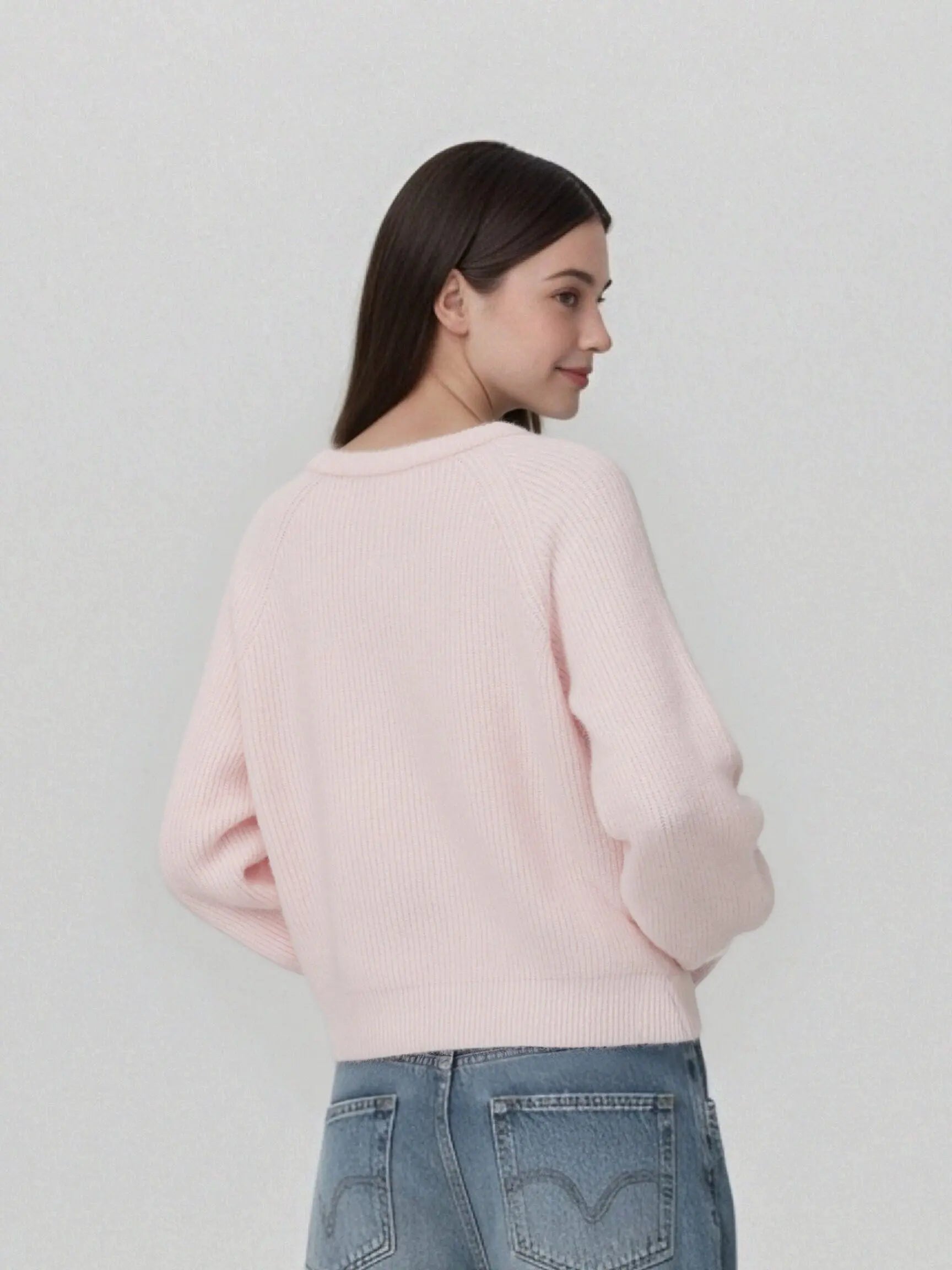 A woman shown from the back wearing a light pink ribbed knit sweater and blue jeans against a plain light gray background. TCH Cute Rhinestone Animal Garden Knit Cardigan