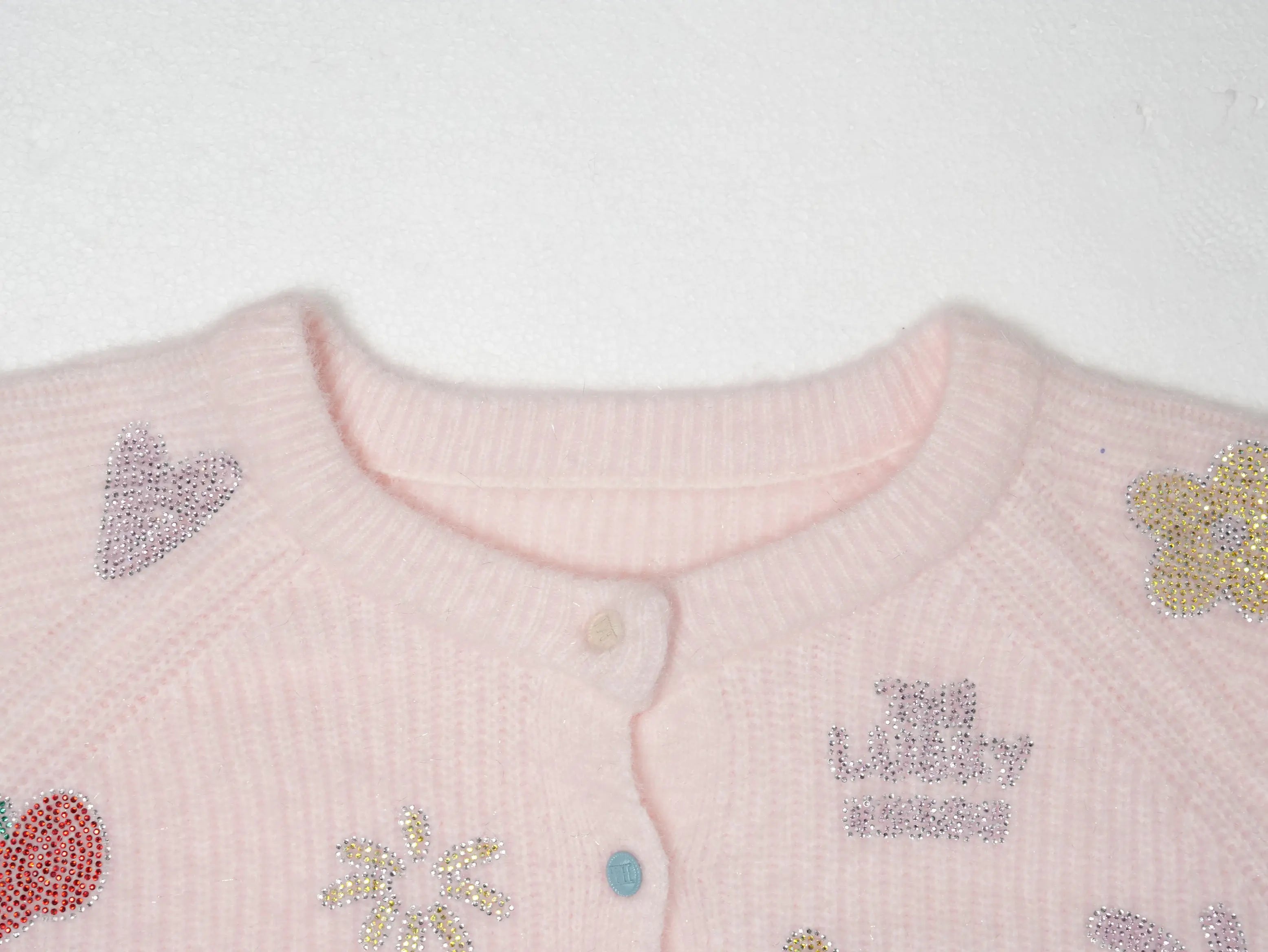 Close-up of a light pink knit cardigan featuring embroidered rhinestone hearts, flowers, and a crown motif with the text 'The Lucky Bunny' on the chest. TCH Cute Rhinestone Animal Garden Knit Cardigan