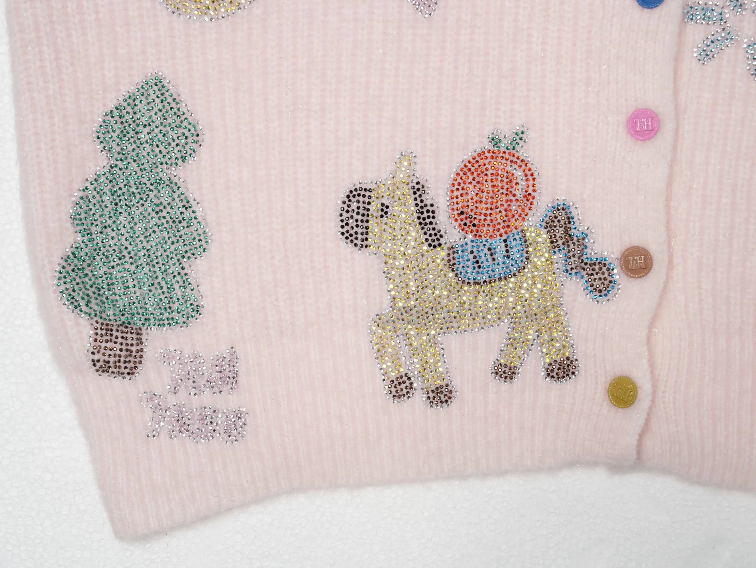 Close-up of a light pink ribbed knit garment featuring decorative rhinestone appliques of a green tree, a yellow horse carrying an orange sack, and colorful buttons along the front. TCH Cute Rhinestone Animal Garden Knit Cardigan