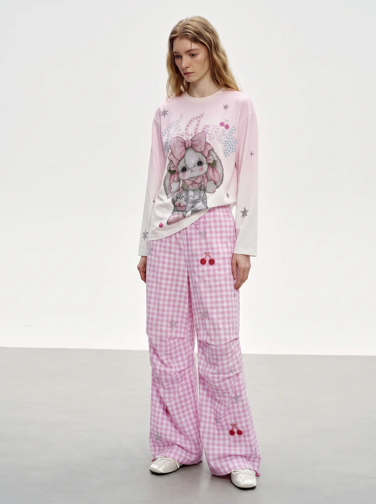 A model wearing a pink and white long-sleeve top with a cartoon bunny graphic and matching pink gingham wide-leg pants, standing against a plain studio background. TCH Cute Rhinestone Cat Graphic Pink Long Sleeve T-Shirt