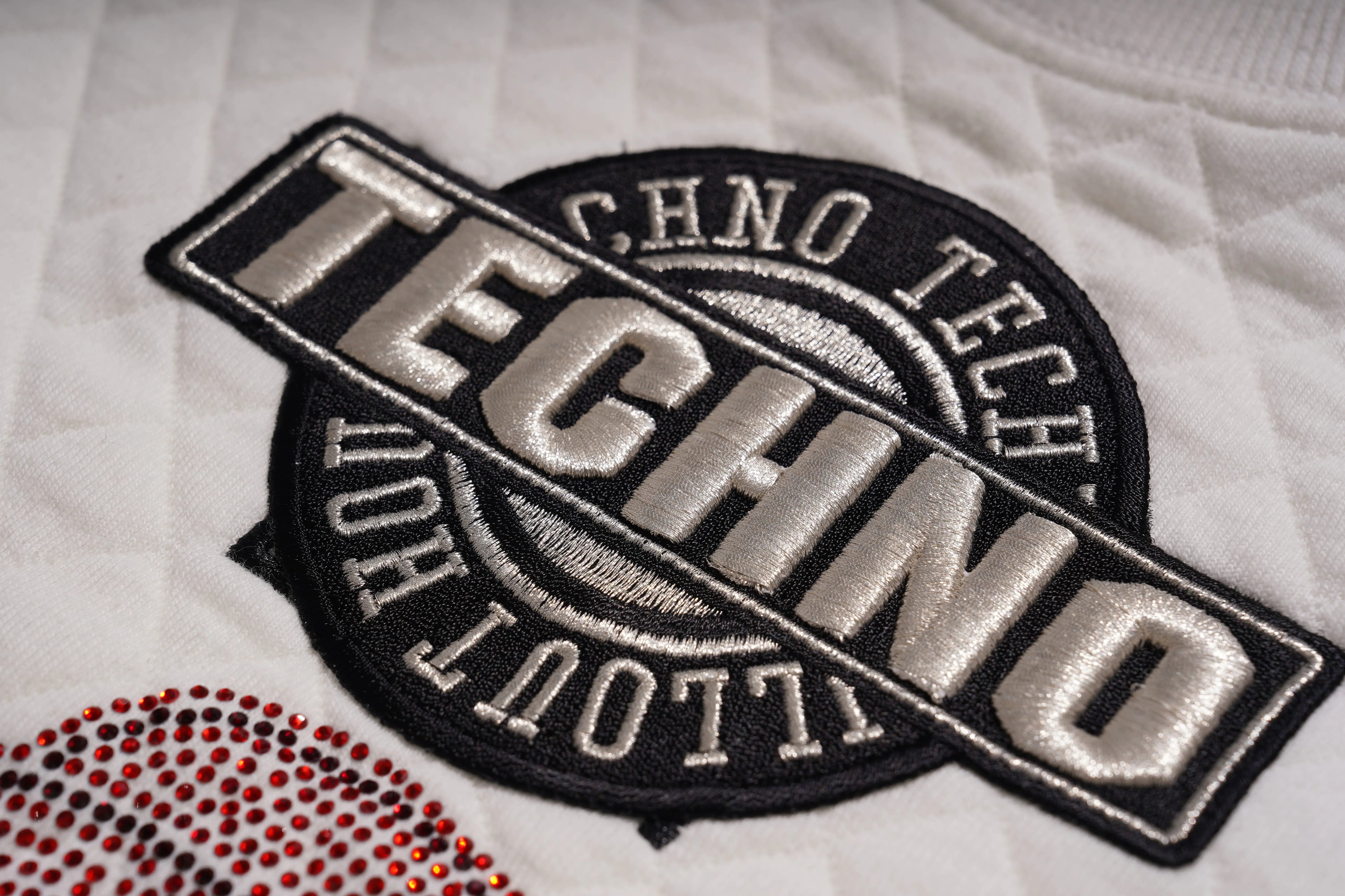 Embroidered patch with 'TECHNO' and 'CHNO TECH' text on a white fabric background. TCH Cute Rhinestone Fortune Pony Sweatshirt