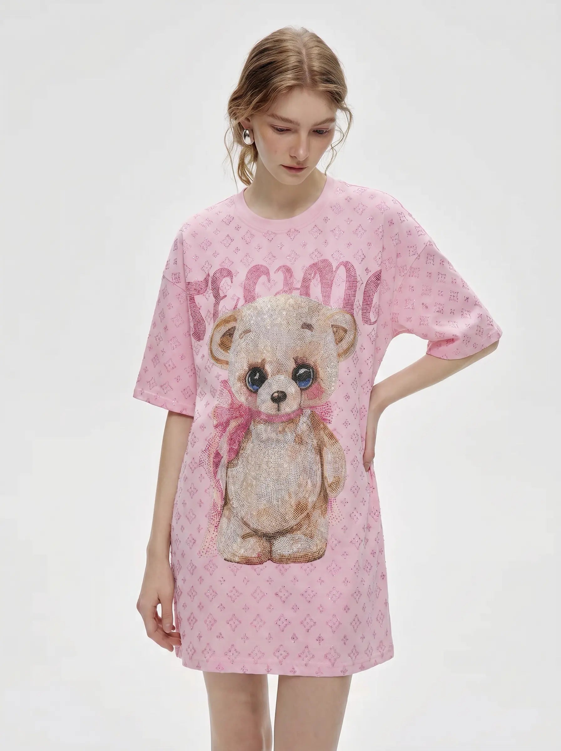 A model wearing a pink short-sleeve t-shirt dress with a teddy bear graphic and 'Femi' text, set against a plain light gray background. TCH Cute Teddy Bear Rhinestone Oversized T-Shirt Dress