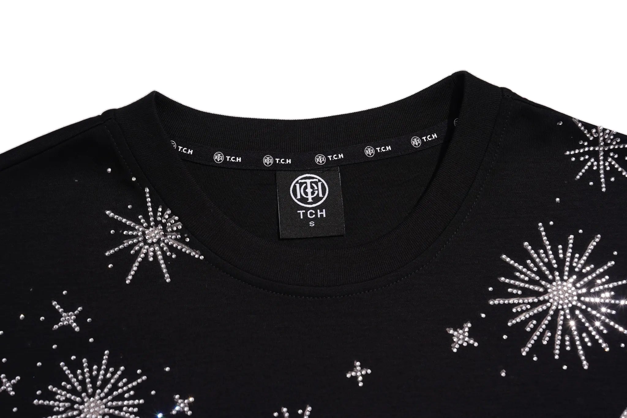Close-up of a black crewneck sweatshirt featuring silver rhinestone starburst and star patterns, with a visible TCH brand label inside the collar. TCH Cute Teddy Bear Rhinestone Oversized T-Shirt Dress