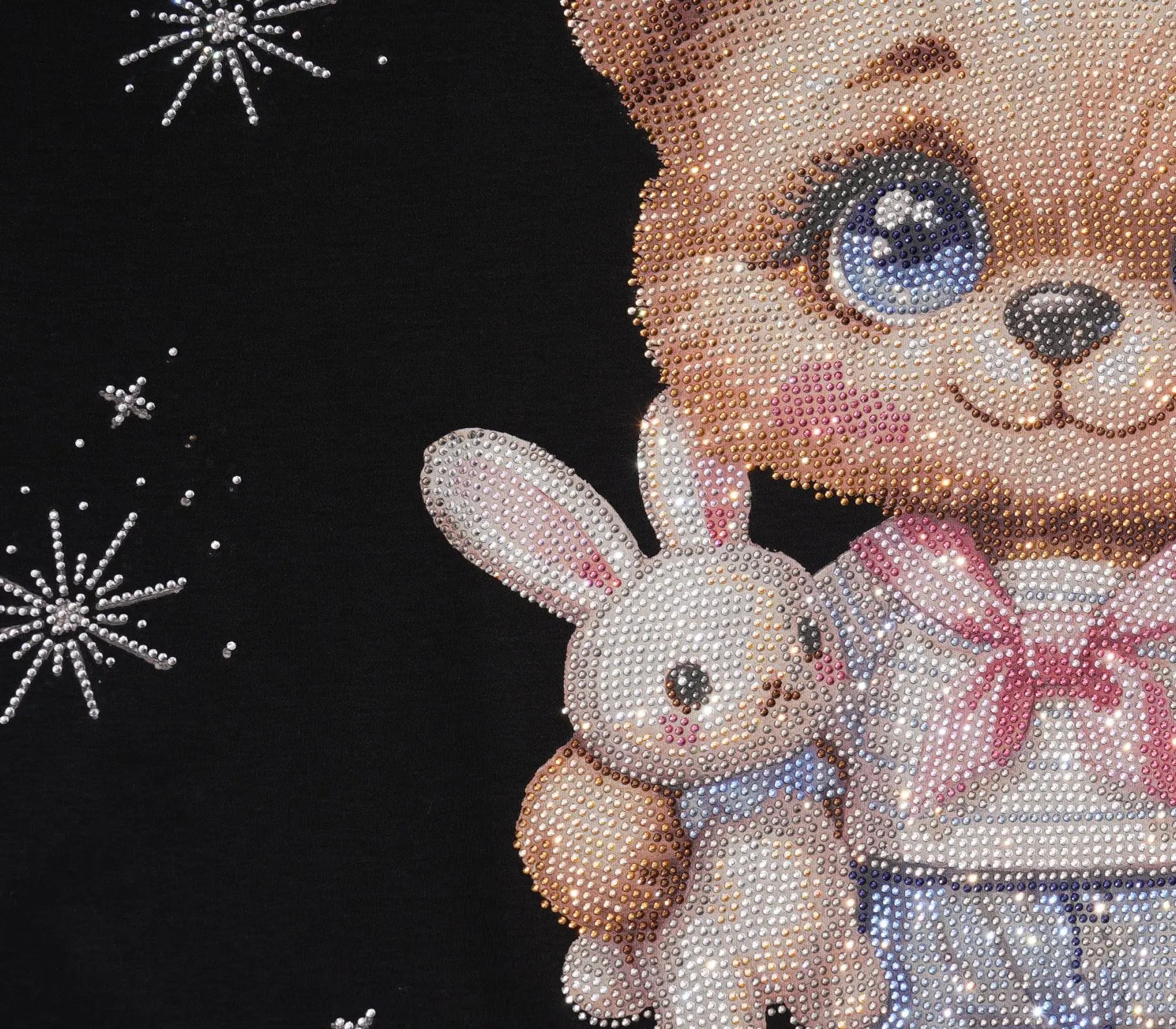 Close-up of a rhinestone-style decorative surface featuring a large brown bear face and upper body holding a white bunny, with a pink bow and blue skirt details against a black background with white starburst accents. TCH Cute Teddy Bear Rhinestone Oversized T-Shirt Dress