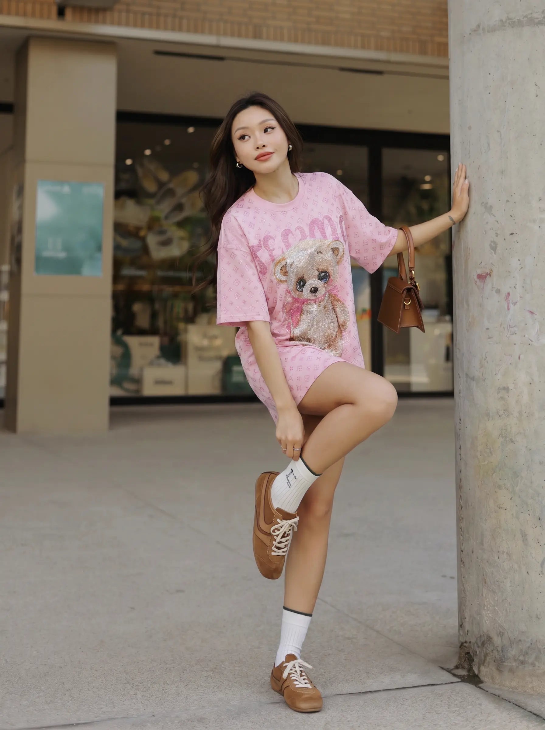 A woman posing outdoors in a pink t-shirt and matching shorts set featuring a teddy bear graphic, paired with brown boat shoes, white socks, and a small brown handbag. TCH Cute Teddy Bear Rhinestone Oversized T-Shirt Dress