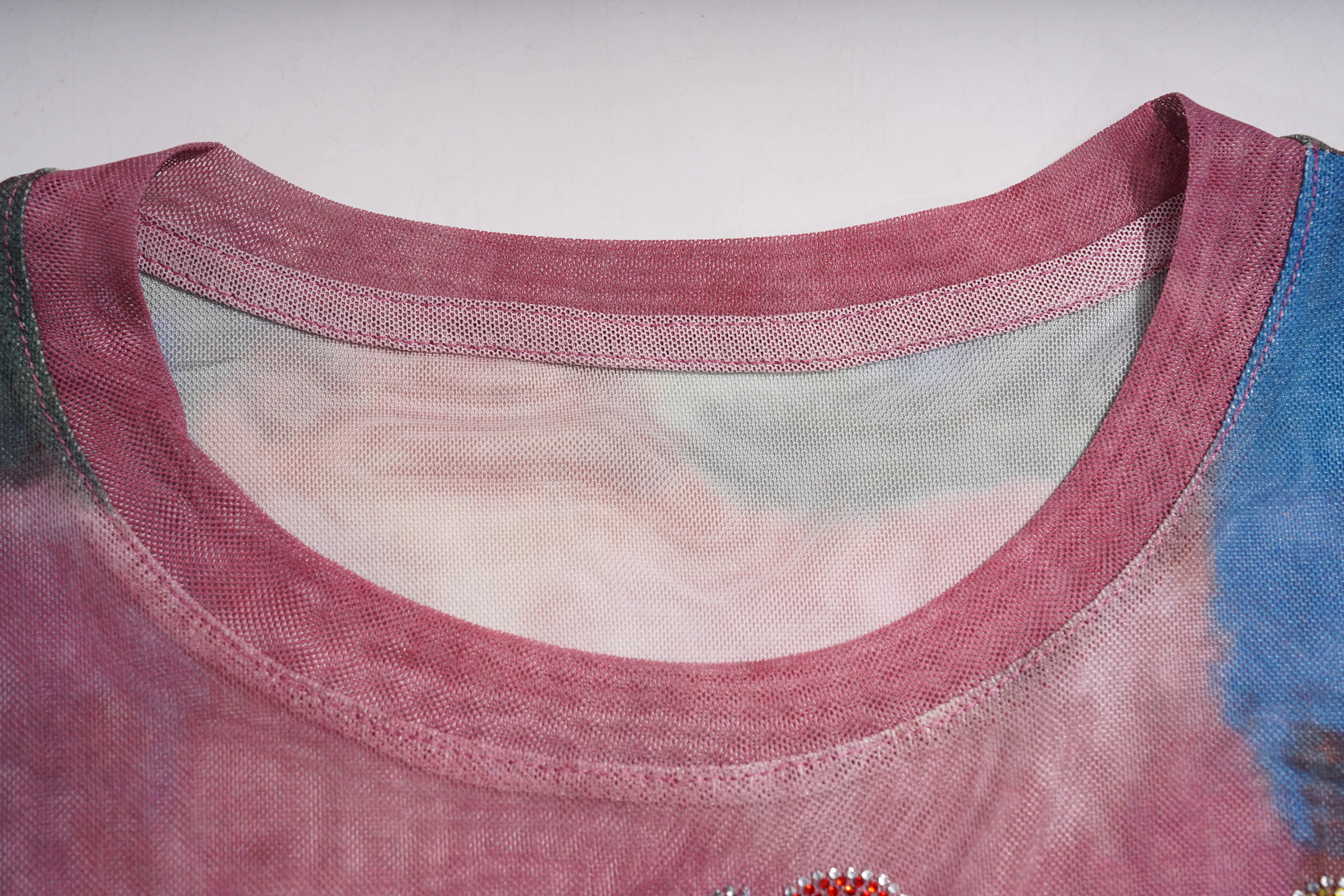 Close-up of a women's scoop neck top showing the dusty rose pink ribbed knit collar, sheer mesh lining, and a hint of a blue and pink printed body. TCH Dream Garden Rhinestone Mesh Long Sleeve Top