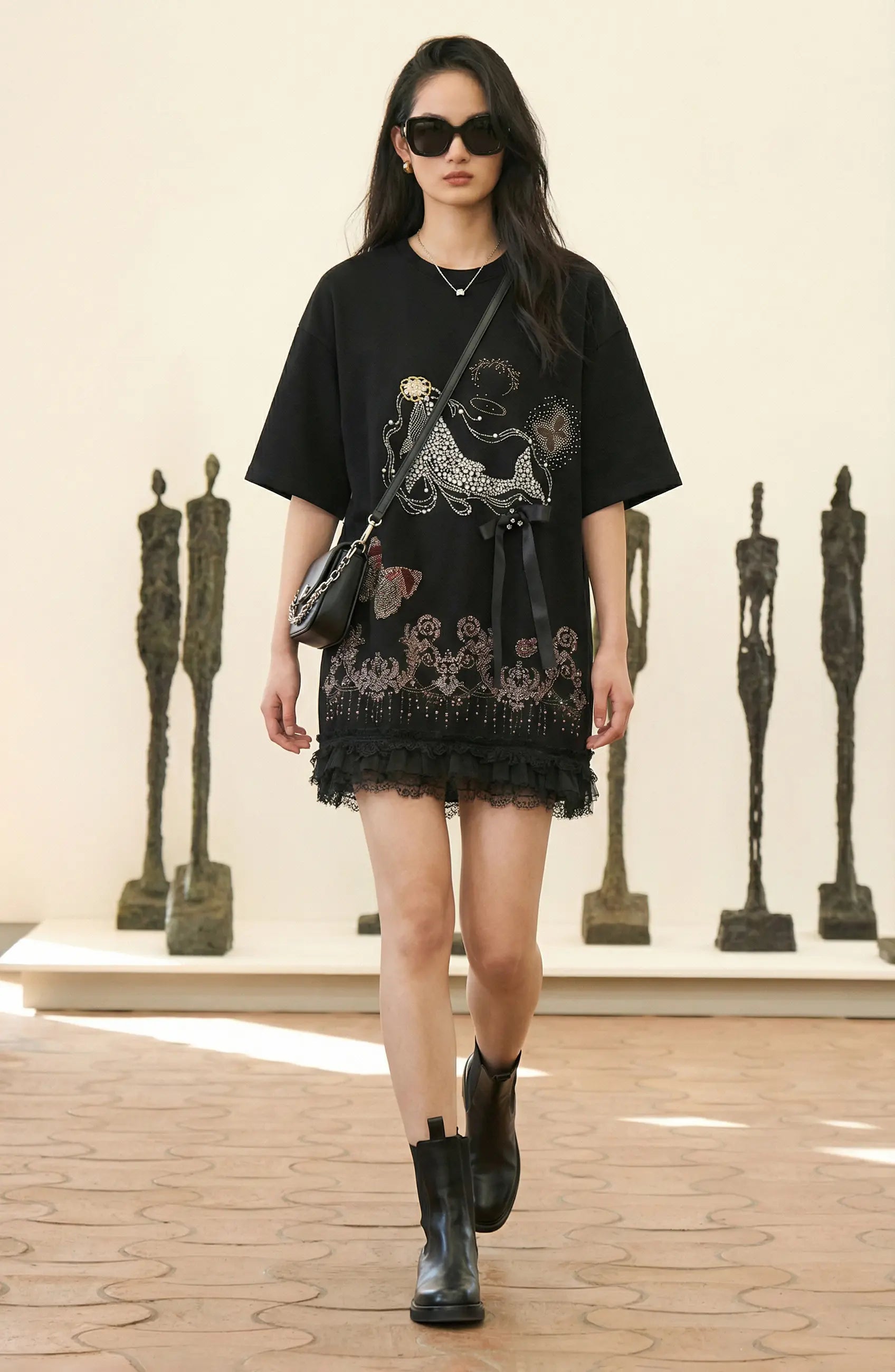 Woman in a black dress with intricate designs standing in an art gallery. TCH Dream Whale Rhinestone Lace Midi Dress
