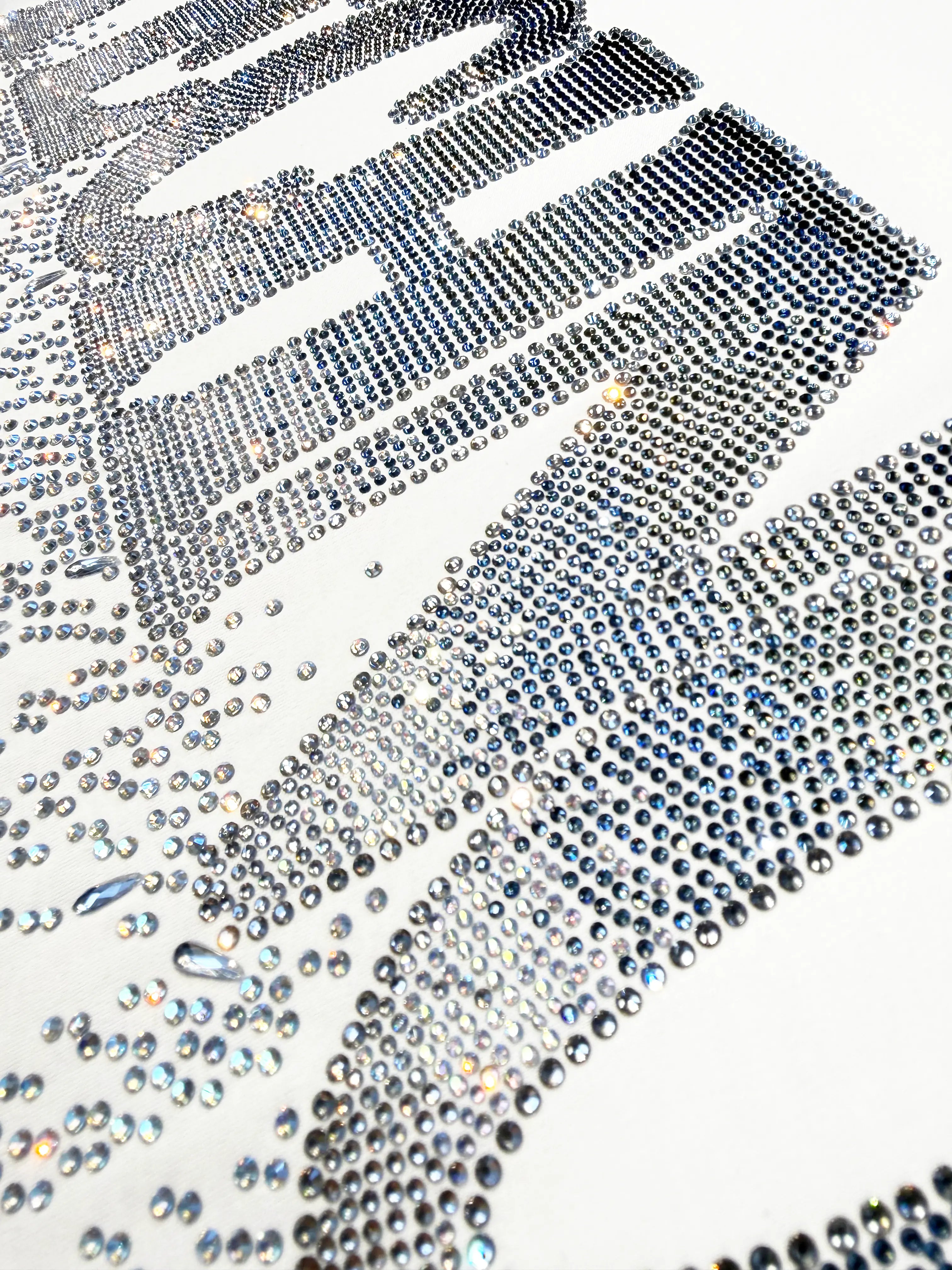 A close-up of a rhinestone-covered surface with large metallic silver lettering on a white background. TCH Dripping Rhinestone Logo Graphic T-Shirt