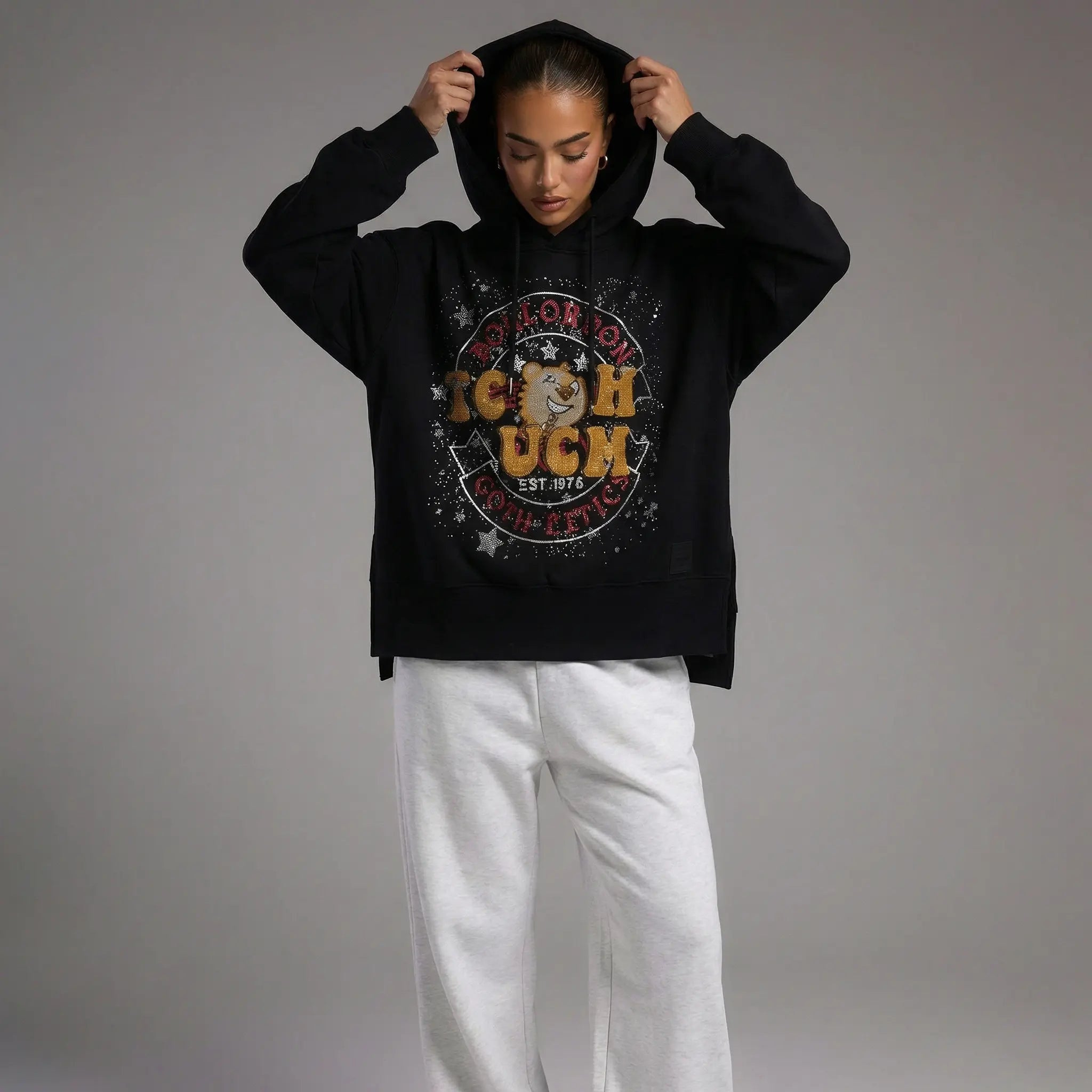 Person wearing a black hoodie with a colorful graphic design on a gray background, TCH Embroidered TCHUCM Rhinestone Hoodie