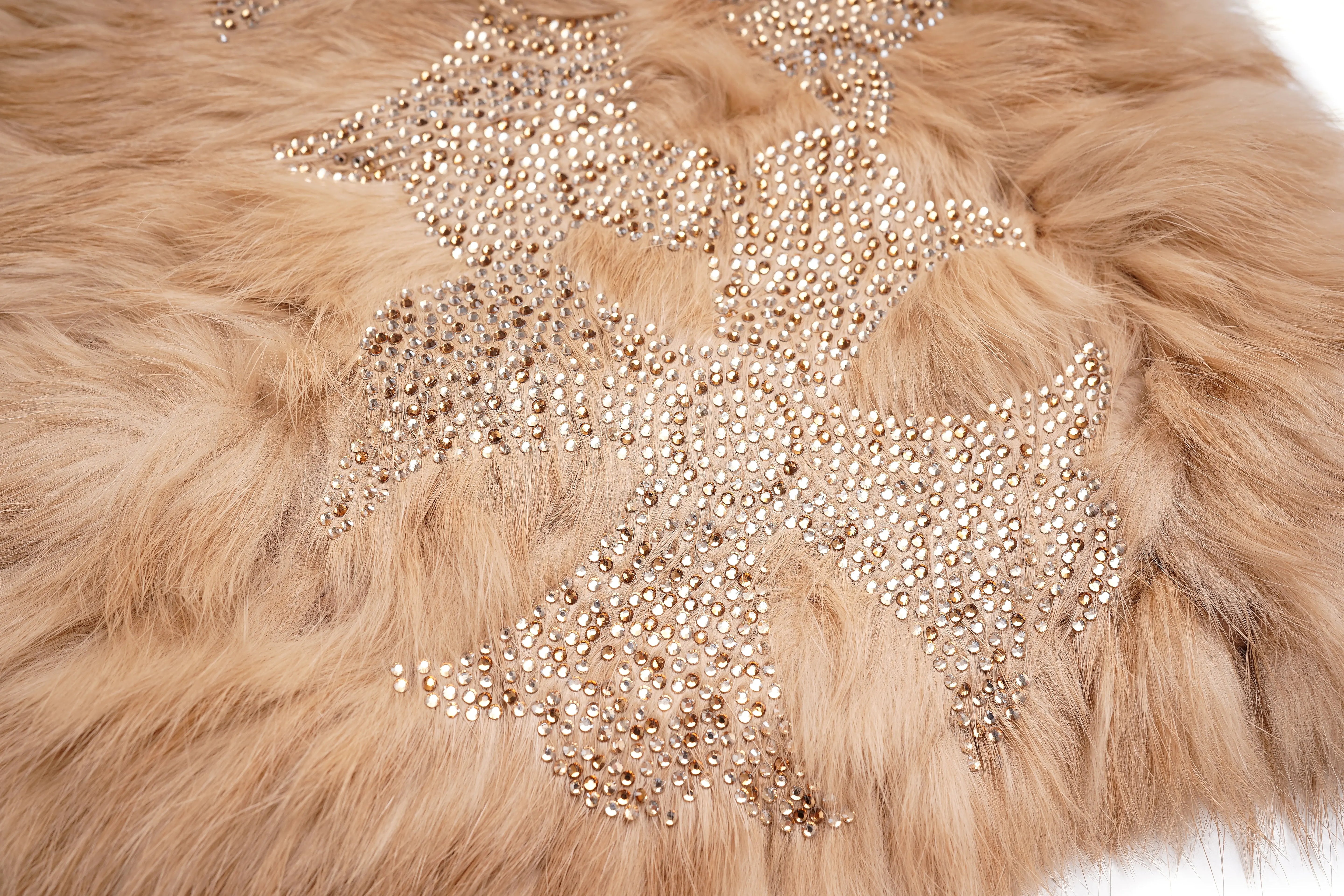 A close-up of a beige faux fur surface decorated with a large star-shaped embellishment made of shimmering gold rhinestones. TCH Faux Fur Rhinestone Knit Tassel Winter Hat