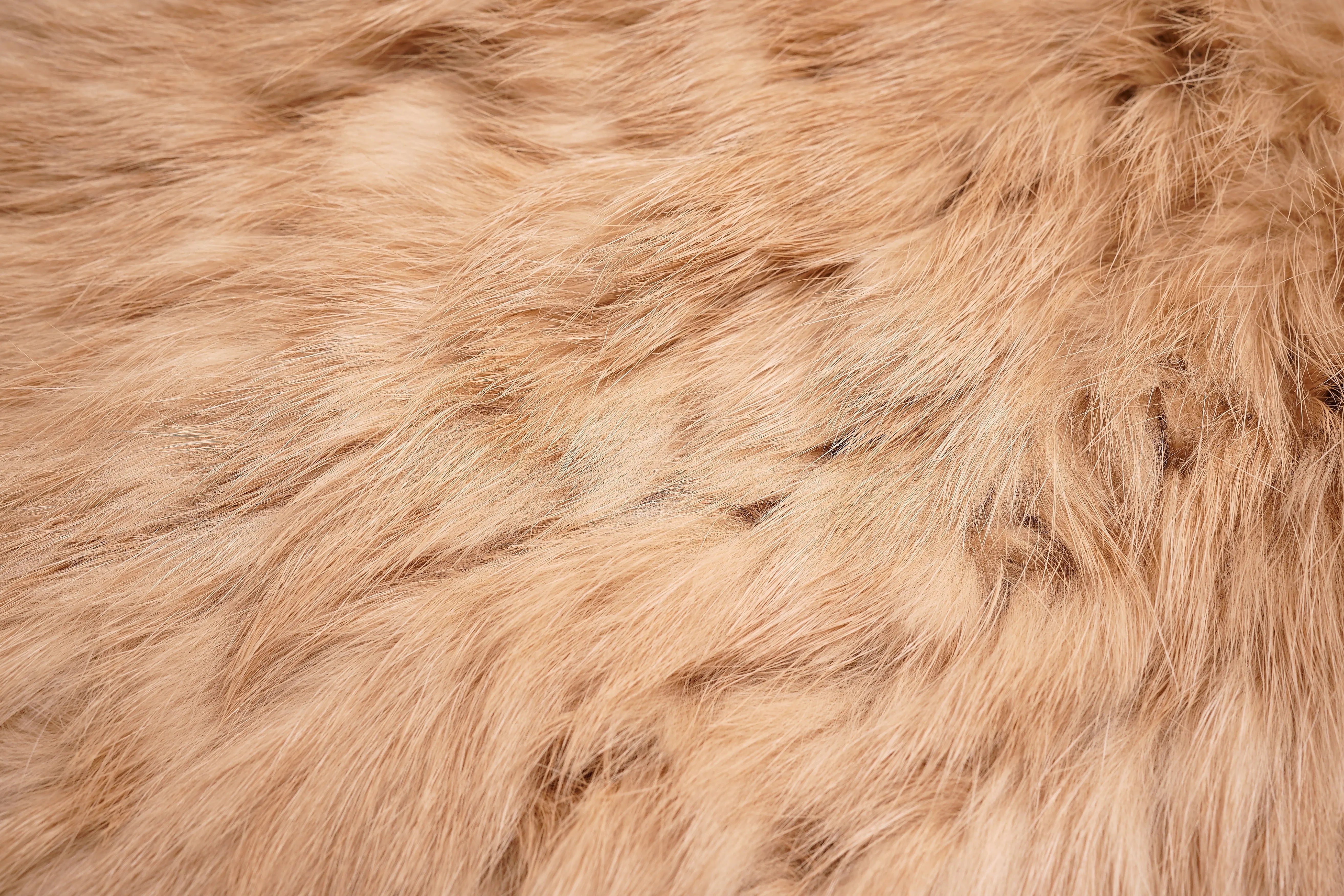 A close-up texture shot of fluffy faux fur fabric in a warm tan or light brown color. TCH Faux Fur Rhinestone Knit Tassel Winter Hat