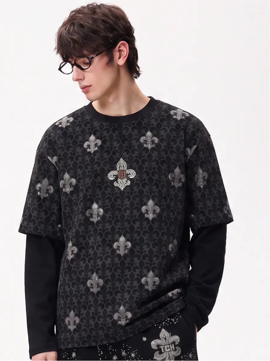 A model wearing a light blue denim jacket with various embroidered patches, including a teddy bear on the left chest and cherries on the sleeve, styled over a white t-shirt and dark pants. TCH Fleur-de-Lis Pattern Layered Long Sleeve T-Shirt