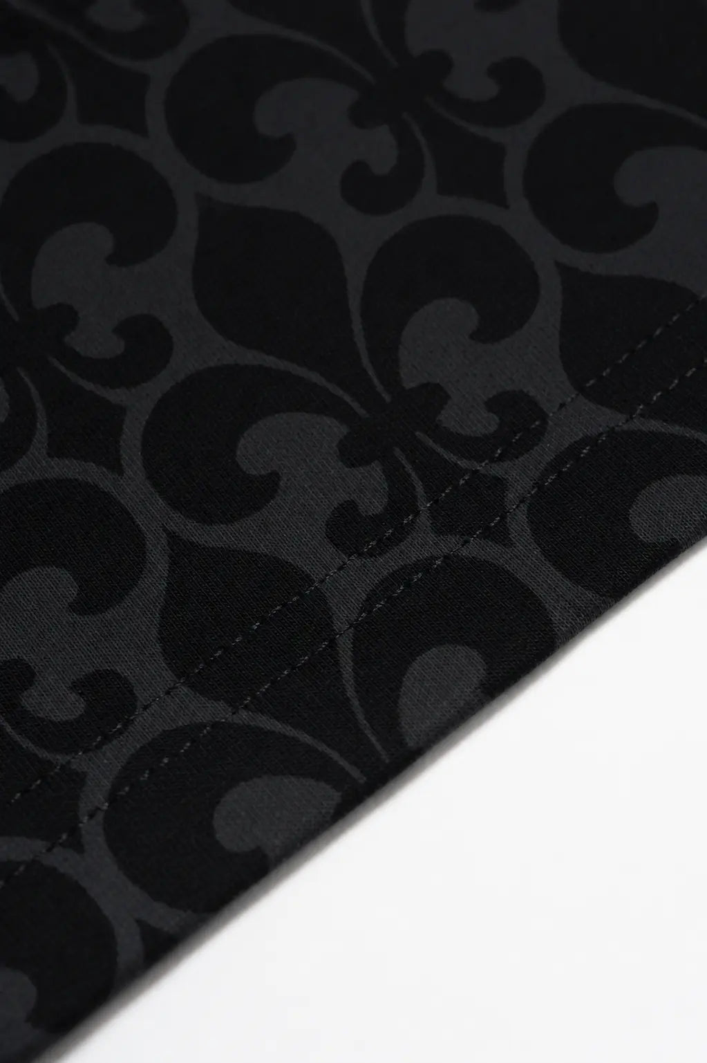 Close-up of a black fabric with a dark gray damask pattern, showing a stitched edge against a white background. TCH Fleur-de-Lis Pattern Layered Long Sleeve T-Shirt