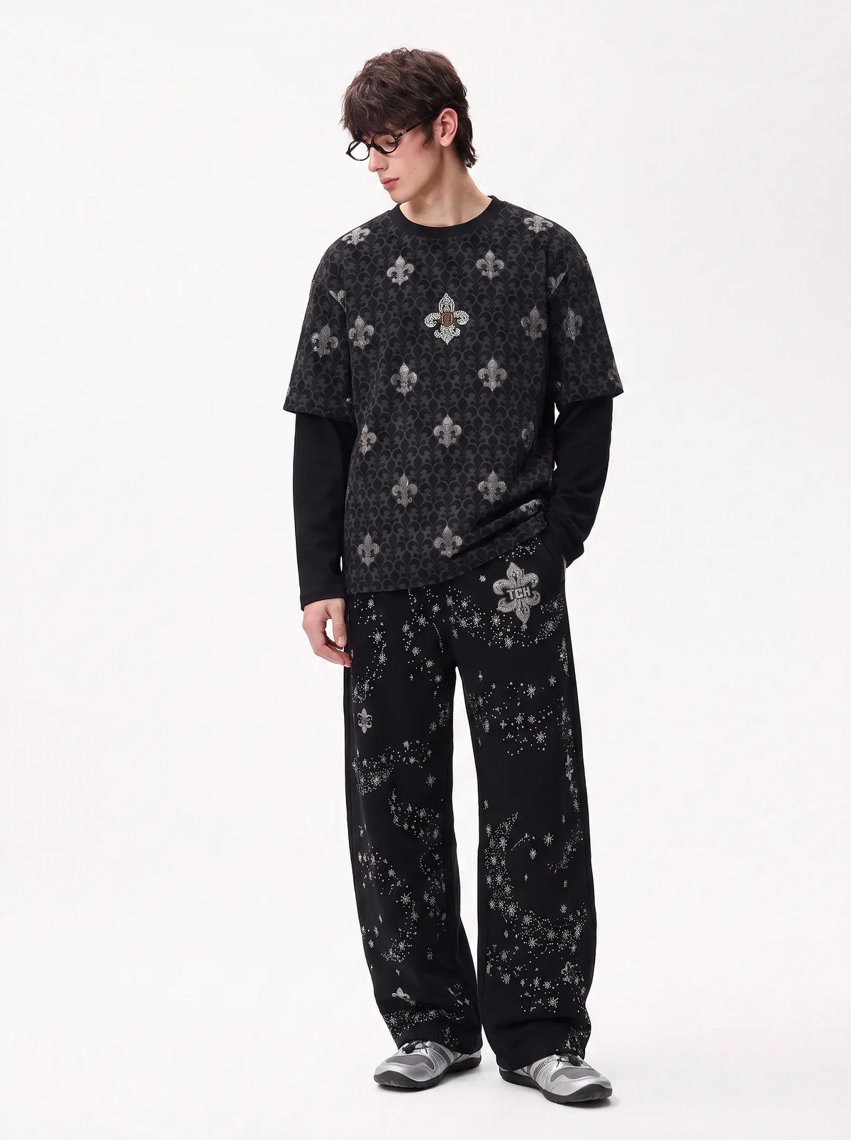 A model wearing a black long-sleeve t-shirt and matching wide-leg pants with a gray and white gothic floral pattern, styled over a black long-sleeve base, against a plain white studio background. TCH Fleur-de-Lis Pattern Layered Long Sleeve T-Shirt