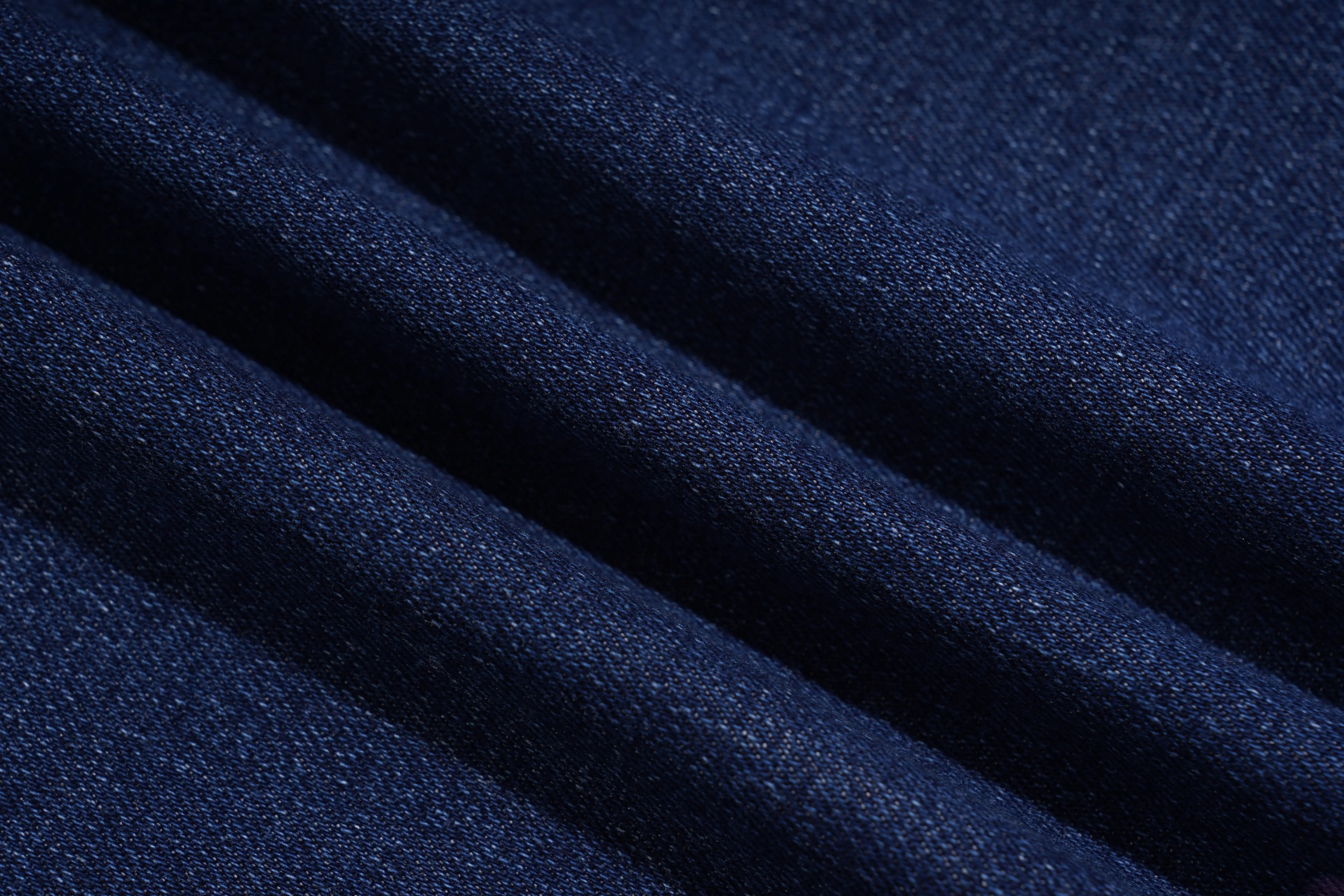 A close-up of dark navy blue textured fabric with soft diagonal folds. TCH Floral Butterfly Print Denim Midi Skirt