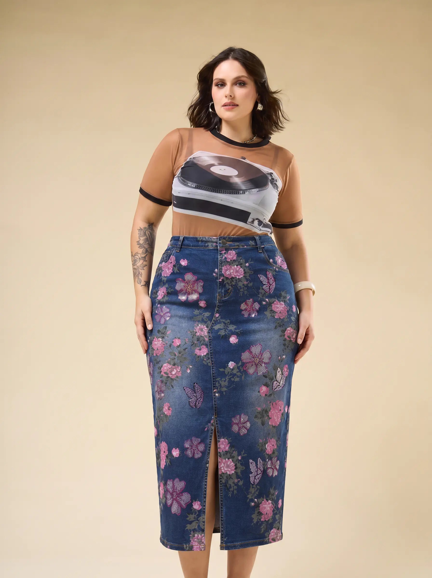 A woman modeling a sheer beige short-sleeve crop top with a vinyl record graphic and a high-waisted blue denim midi skirt with a pink floral print, set against a solid beige studio background. TCH Floral Butterfly Print Denim Midi Skirt