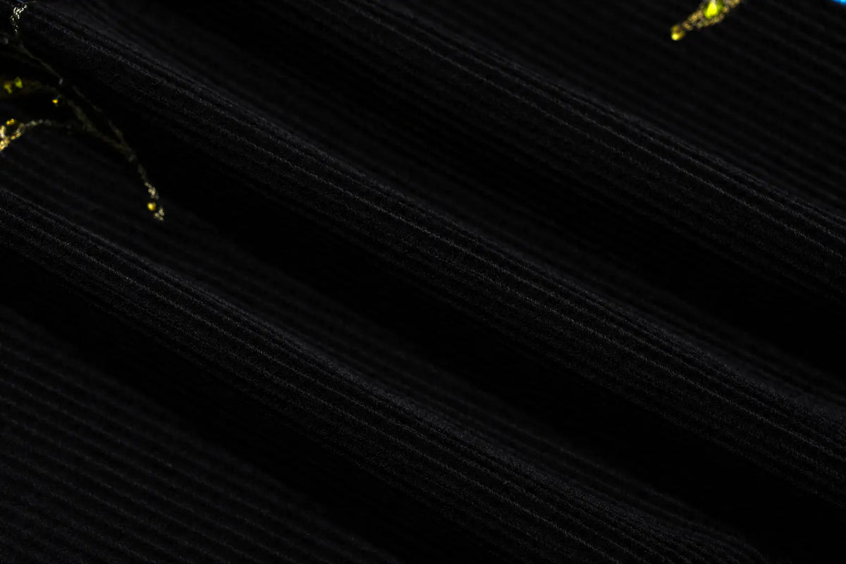 A close-up of black ribbed fabric with diagonal texture lines and small gold glittery accents. TCH Floral Embroidered Techno Corduroy Mini Skirt