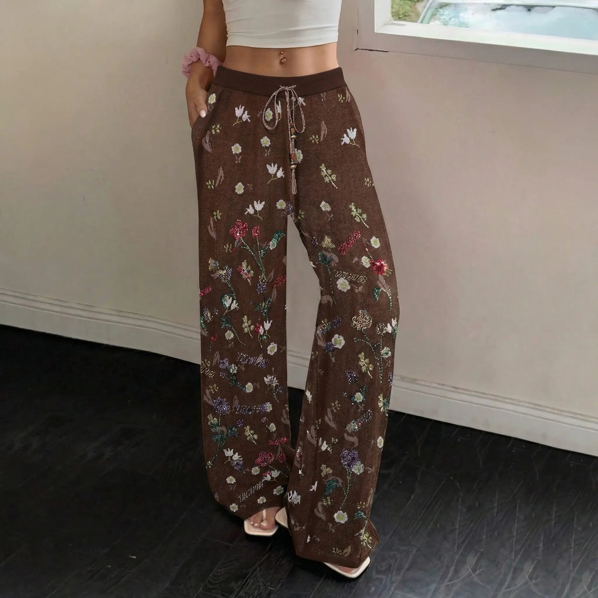 Person wearing brown floral-patterned pants indoors. TCH Floral Rhinestone Accent Sweatpants
