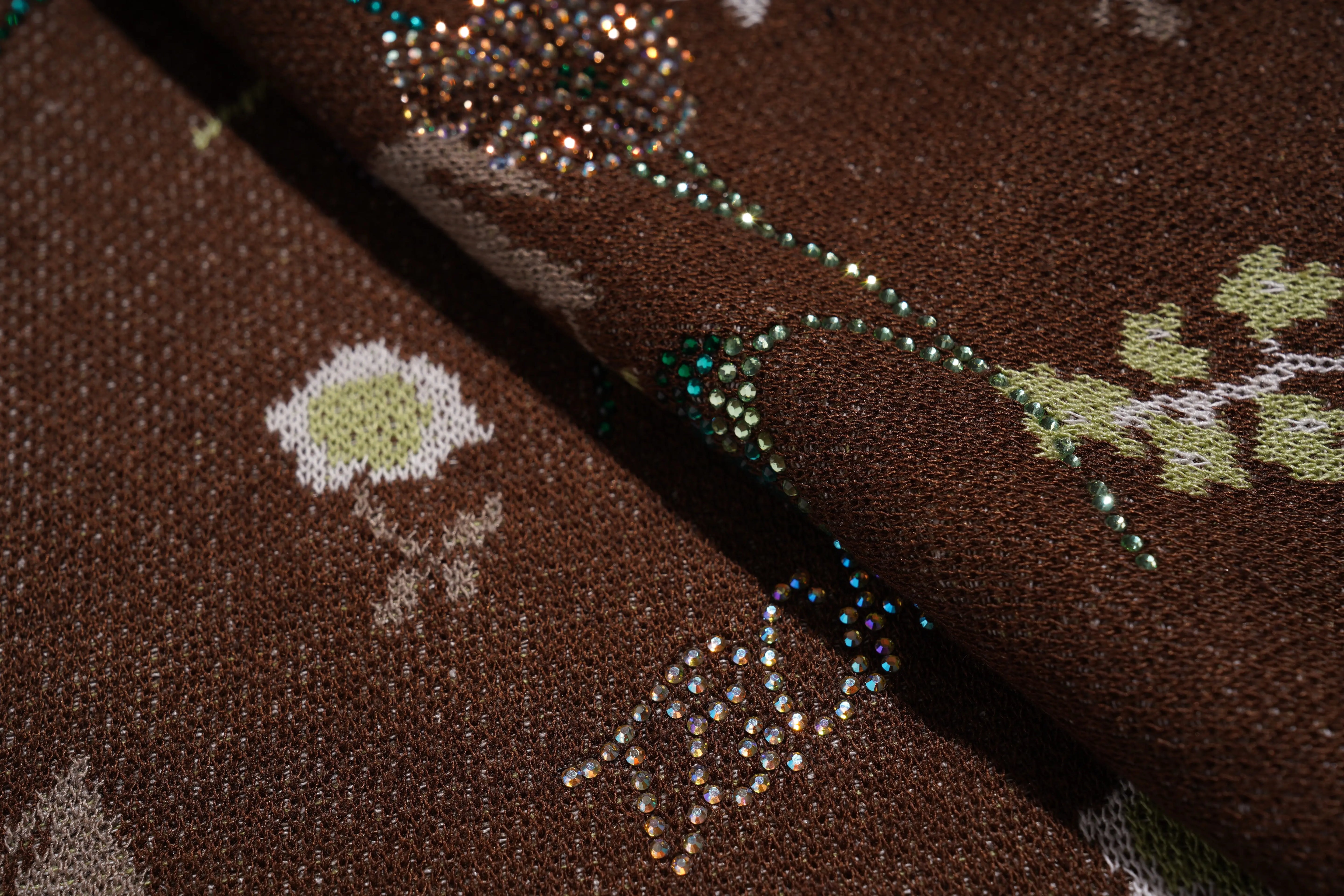 Close-up of a fabric with floral patterns and rhinestones on a brown background, TCH Floral Rhinestone Accent Sweatpants