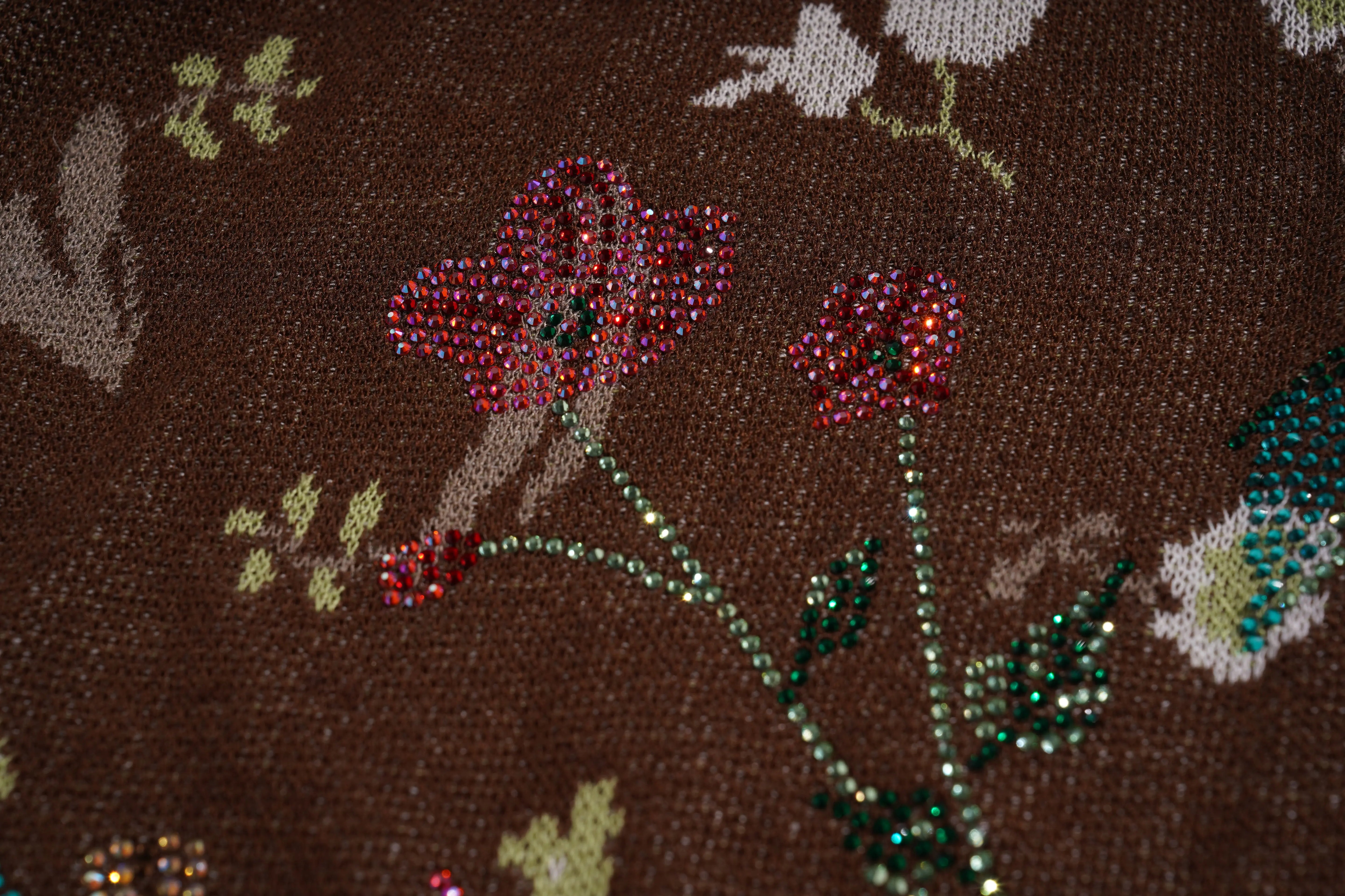 Close-up of a brown fabric with floral patterns and rhinestone embellishments. TCH Floral Rhinestone Accent Sweatpants
