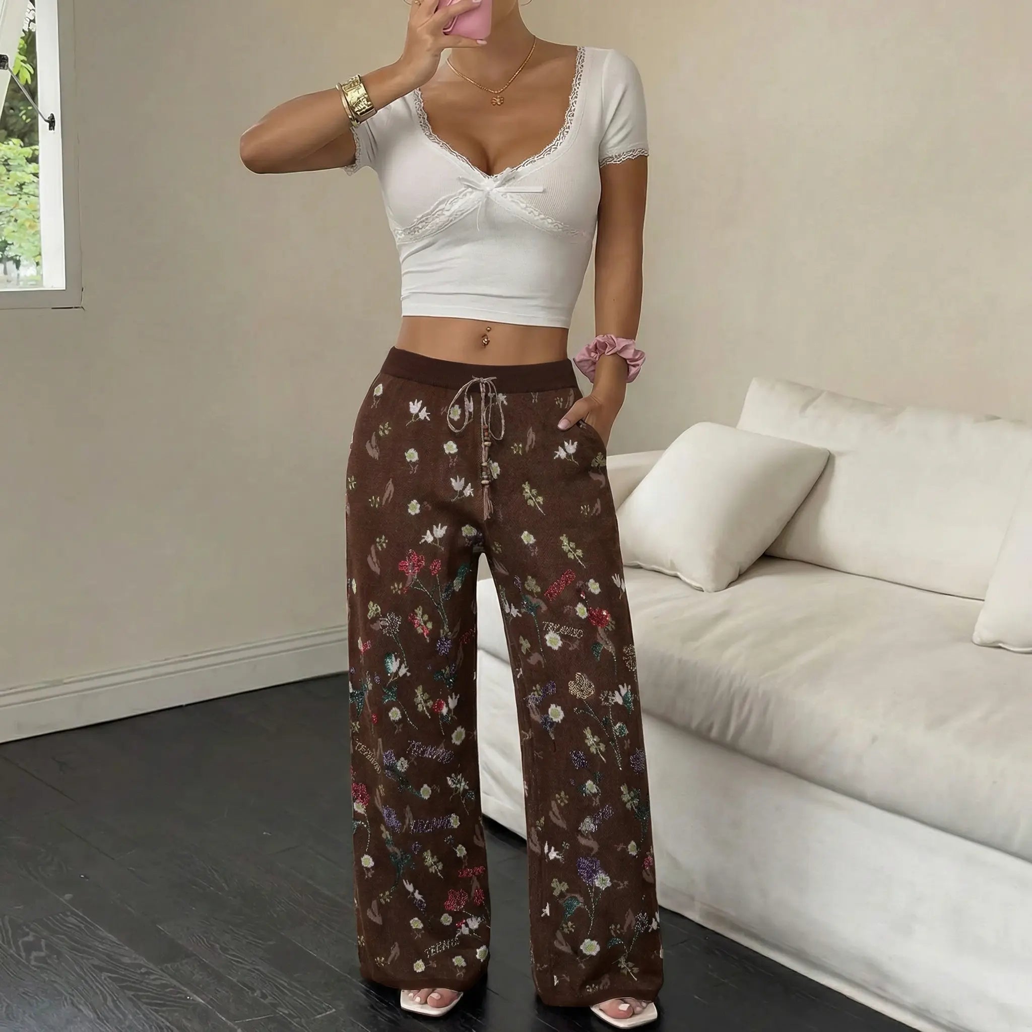 Person wearing a white top and brown floral pants in a living room. TCH Floral Rhinestone Accent Sweatpants