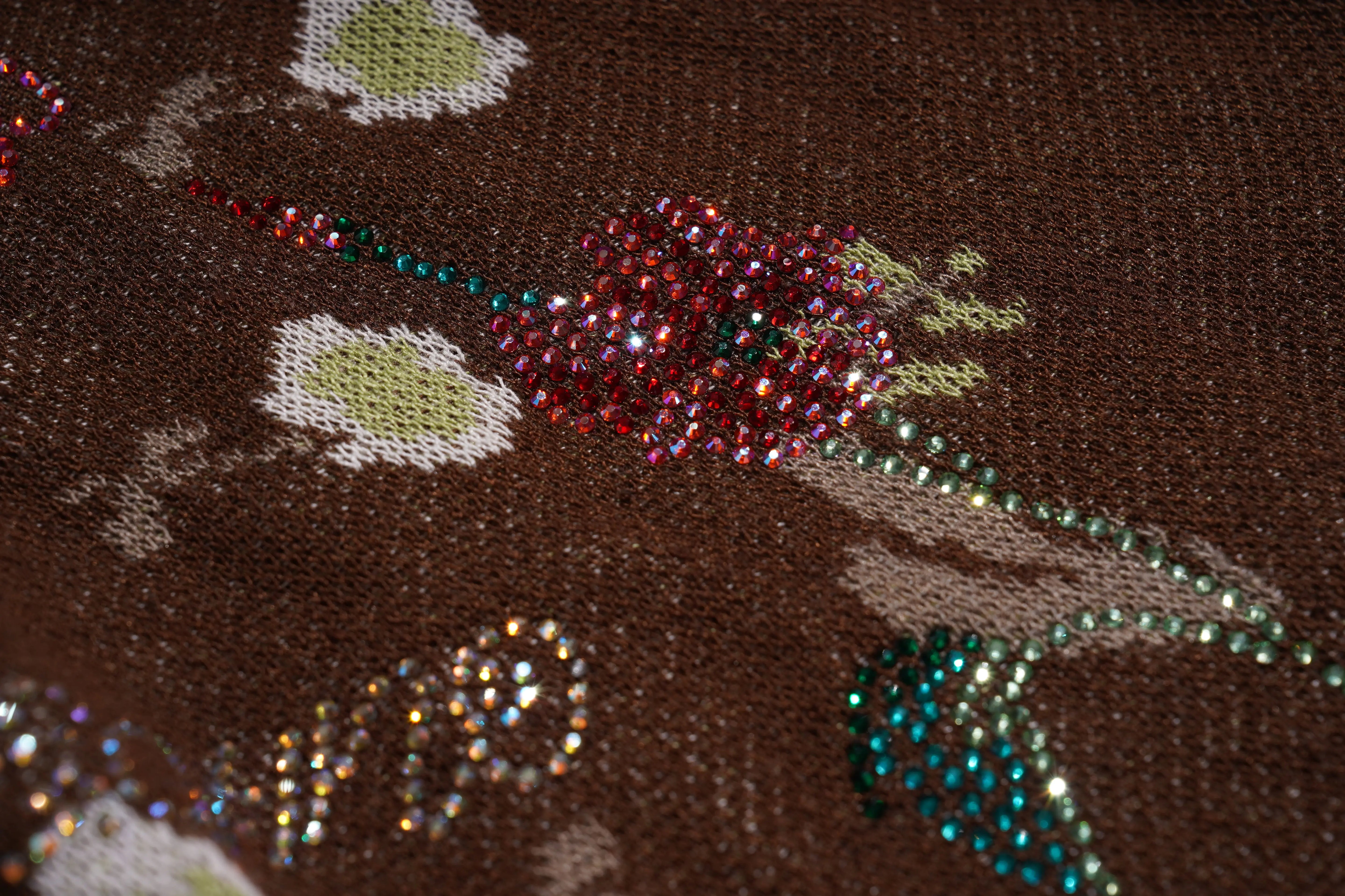 Close-up of a decorative fabric with floral patterns and rhinestones on a brown background, TCH Floral Rhinestone Accent Sweatpants