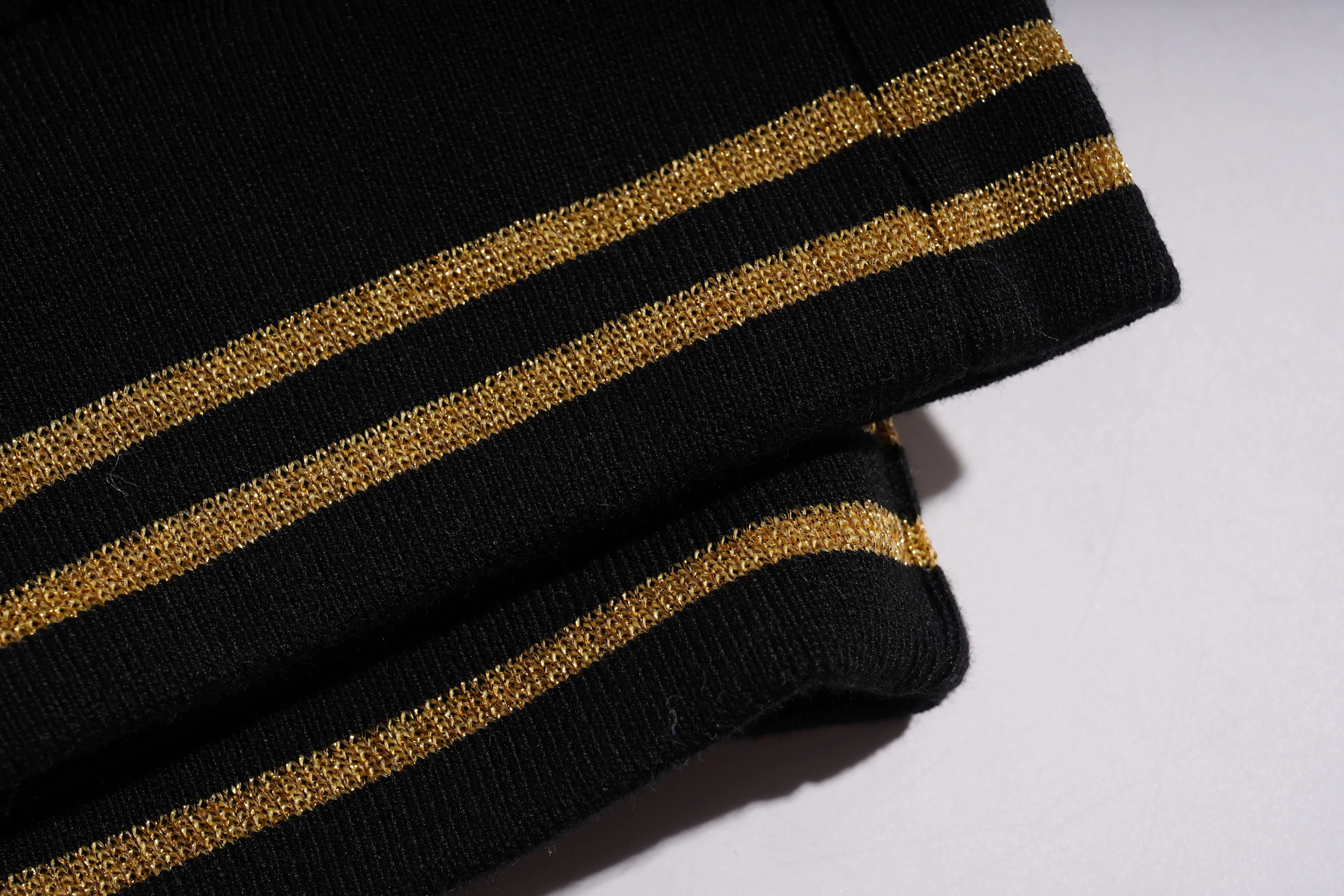 Close-up of black fabric with gold stripes on a white background, TCH Galaxy Rhinestone Black Jogger Pants Luxury Streetwear Brand Official Showcase