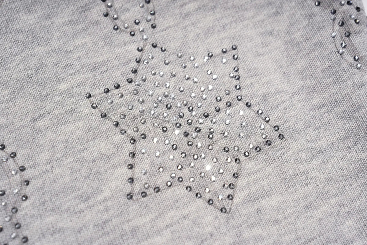 Close-up of a light gray knit fabric with a star-shaped embellishment made of small dark and silver rhinestones. TCH Gothic Rhinestone Lace Pattern Flared Sleeve Long Sleeve Top