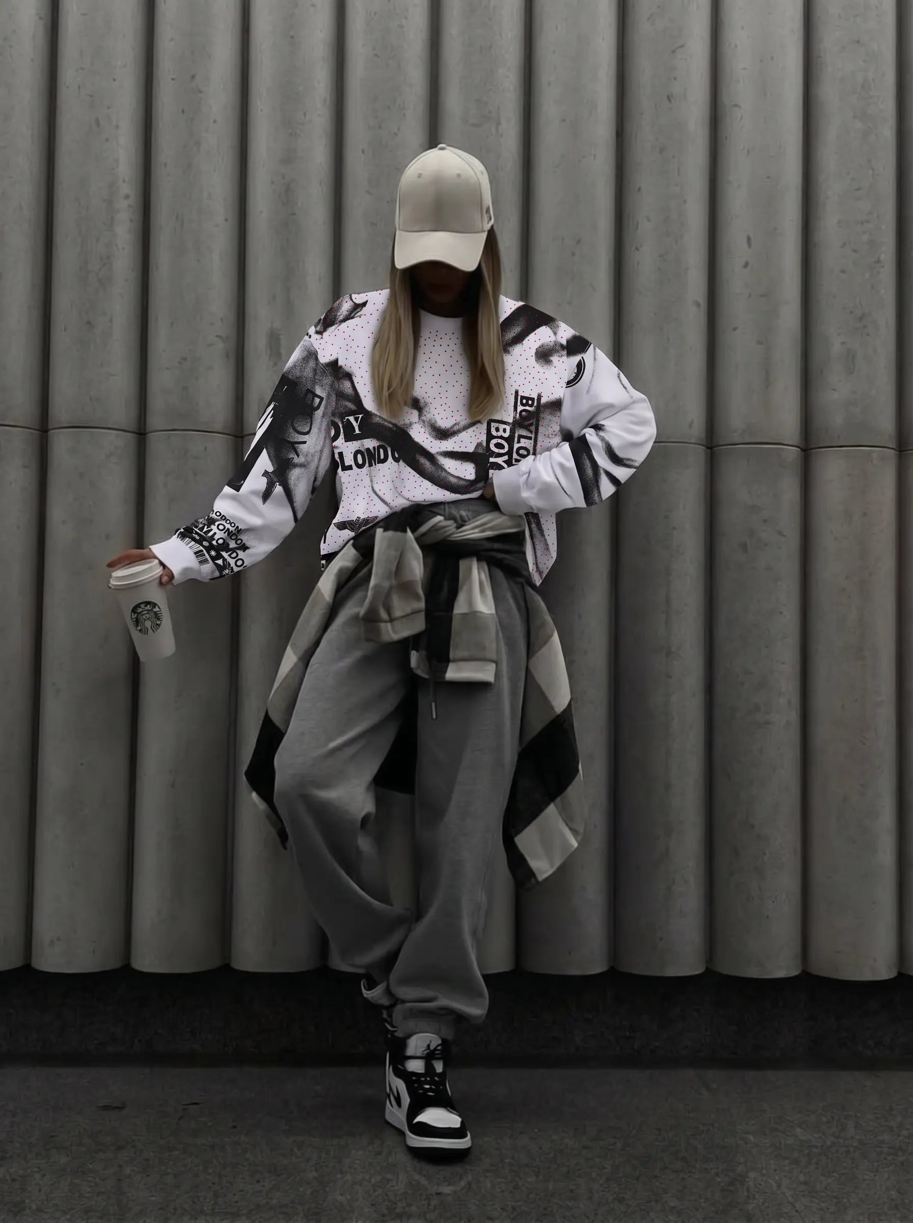 Person wearing a stylish outfit with a graphic jacket and cap, standing against a gray wall. TCH Graffiti Logo Print Crewneck Sweatshirt