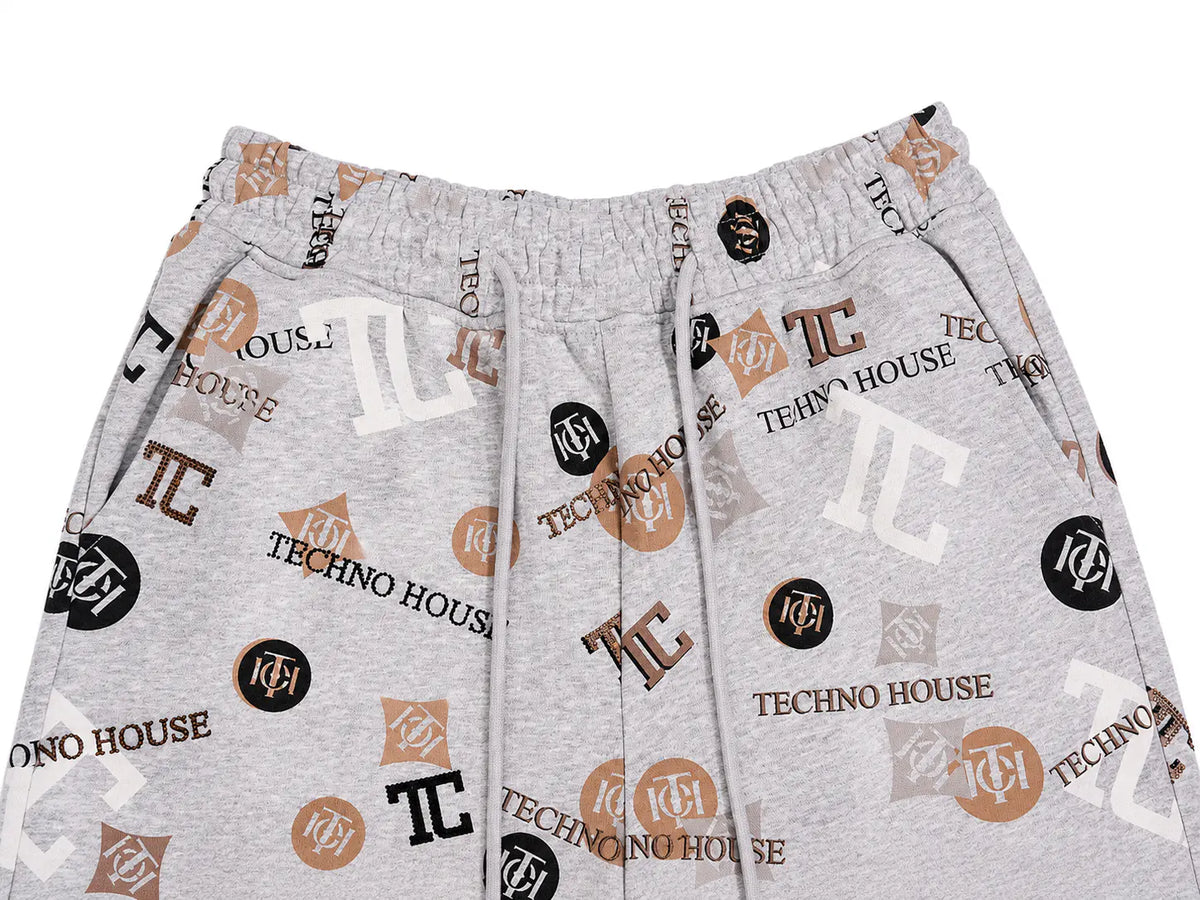 Light gray heather sweatpants featuring an all-over 'TECHNO HOUSE' and 'TC' logo print in brown, black, and white, with an elastic waistband and drawstrings. TCH Gray Techno Graphic Wide-Leg Sweatpants
