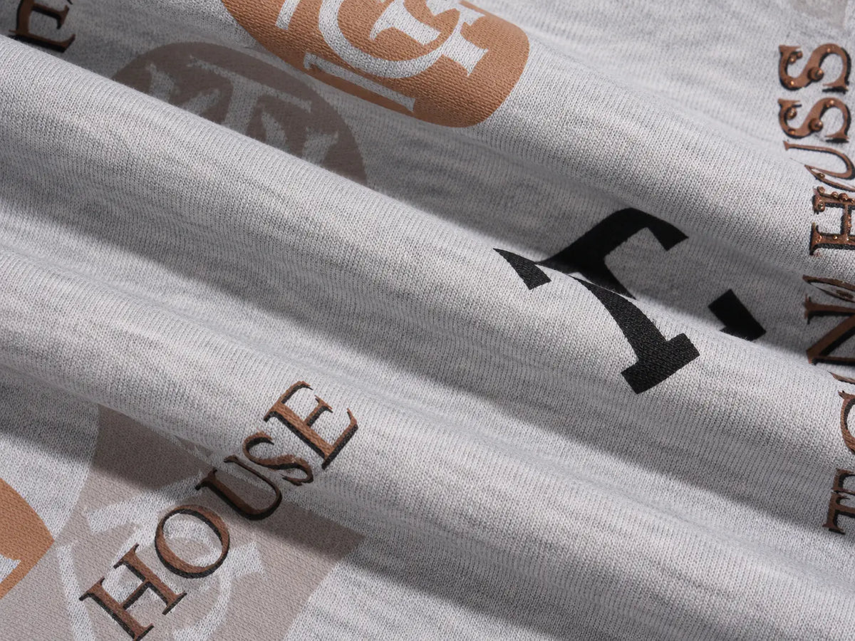 Close-up of a light gray ribbed fabric with a repeating printed pattern featuring black letters and brown/tan text and logo elements. TCH Gray Techno Graphic Wide-Leg Sweatpants