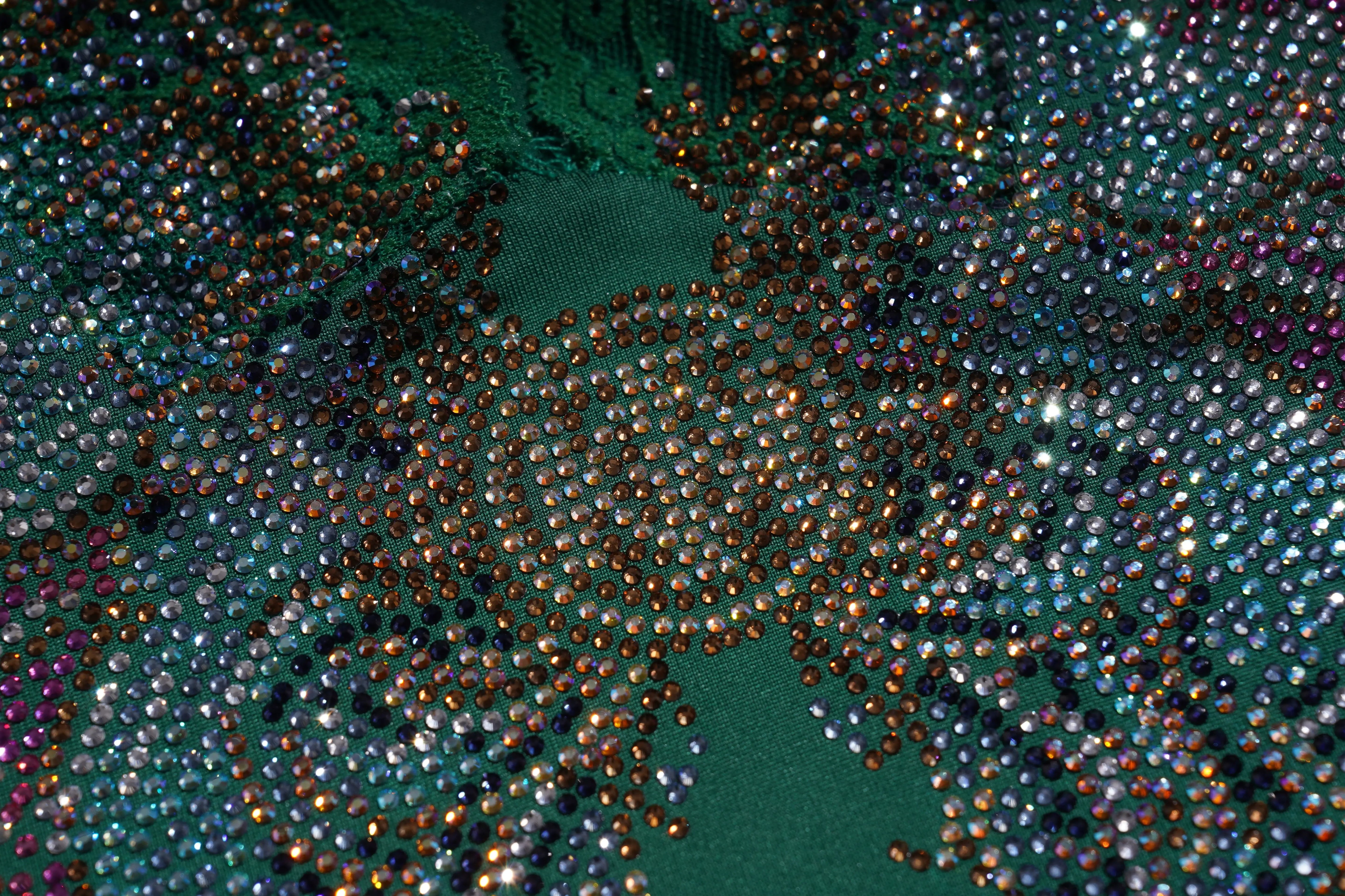 Close-up of a textured green fabric with small beads or stones. TCH Green Lace Trim V-Neck Rhinestone Wing Long Sleeve Top