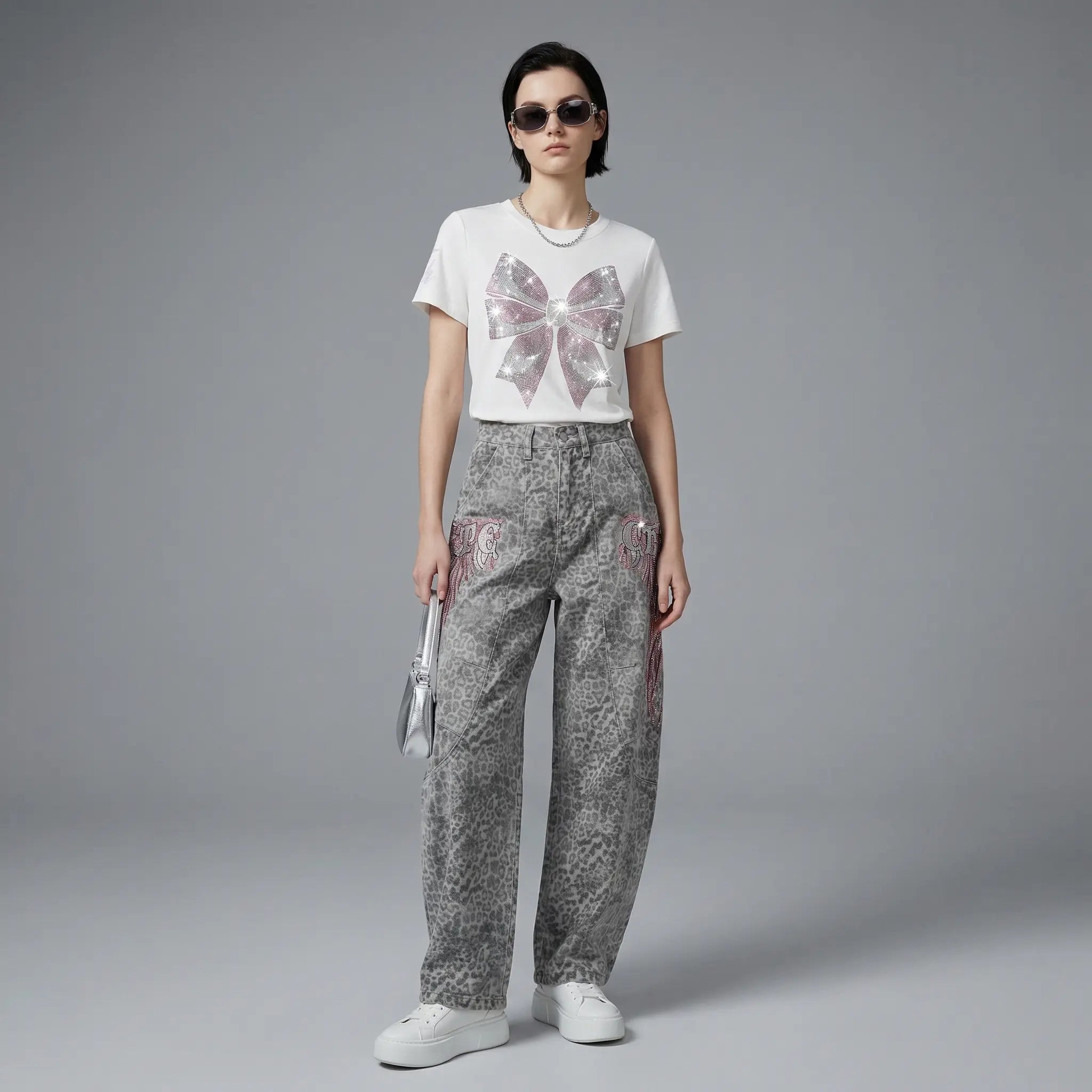 Person wearing a white t-shirt with a butterfly design and patterned pants on a gray background, TCH Grey Leopard Rhinestone Wings Wide-Leg Jeans