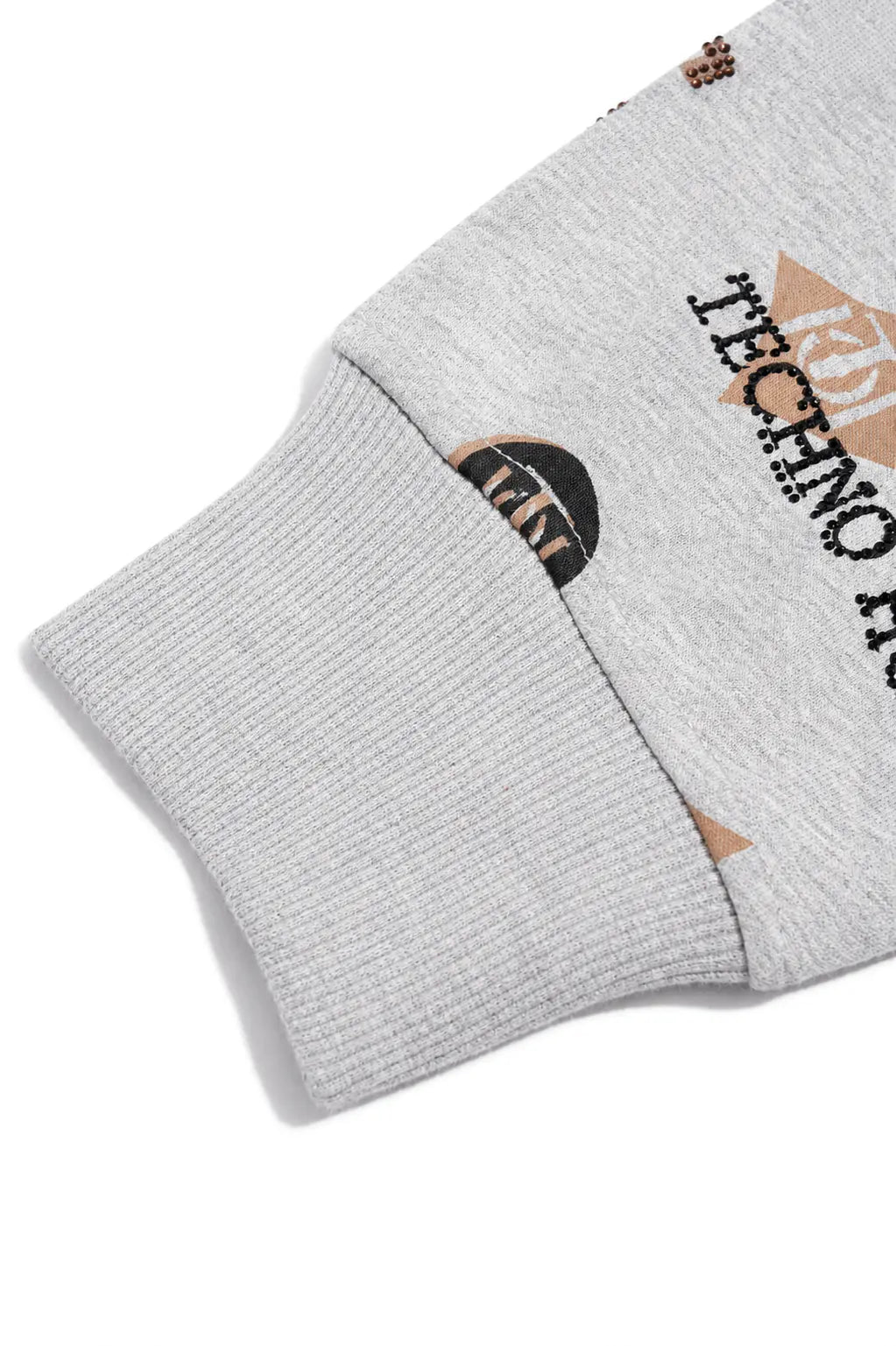 Close-up of a light gray ribbed knit sleeve with black and tan printed graphics and text, including 'TECHNO' and a circular logo, on a white background. TCH Grey Logo Print Zip Hoodie