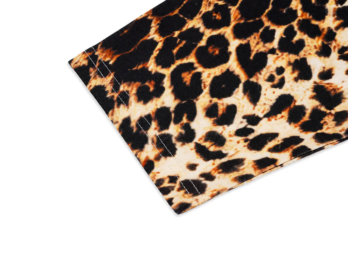 A close-up of a leopard print fabric corner showing a stitched edge, with a black, brown, and beige animal pattern on a white background. TCH Leopard Print Sleeve Embellished Cross Raglan Long Sleeve T-Shirt