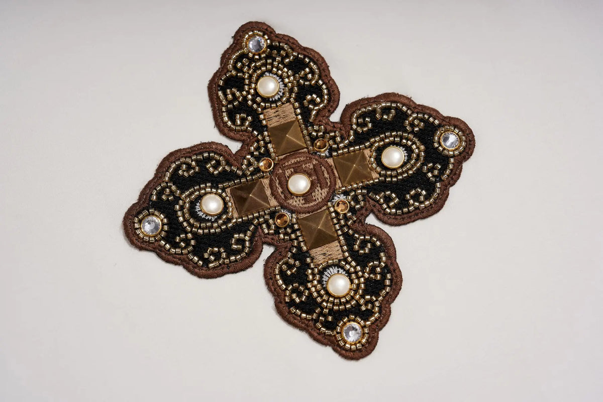 An ornate cross-shaped embroidered patch or brooch with a dark brown and black velvet background, detailed with gold metallic embroidery, small pearls, and rhinestones on a plain light background. TCH Leopard Print Sleeve Embellished Cross Raglan Long Sleeve T-Shirt